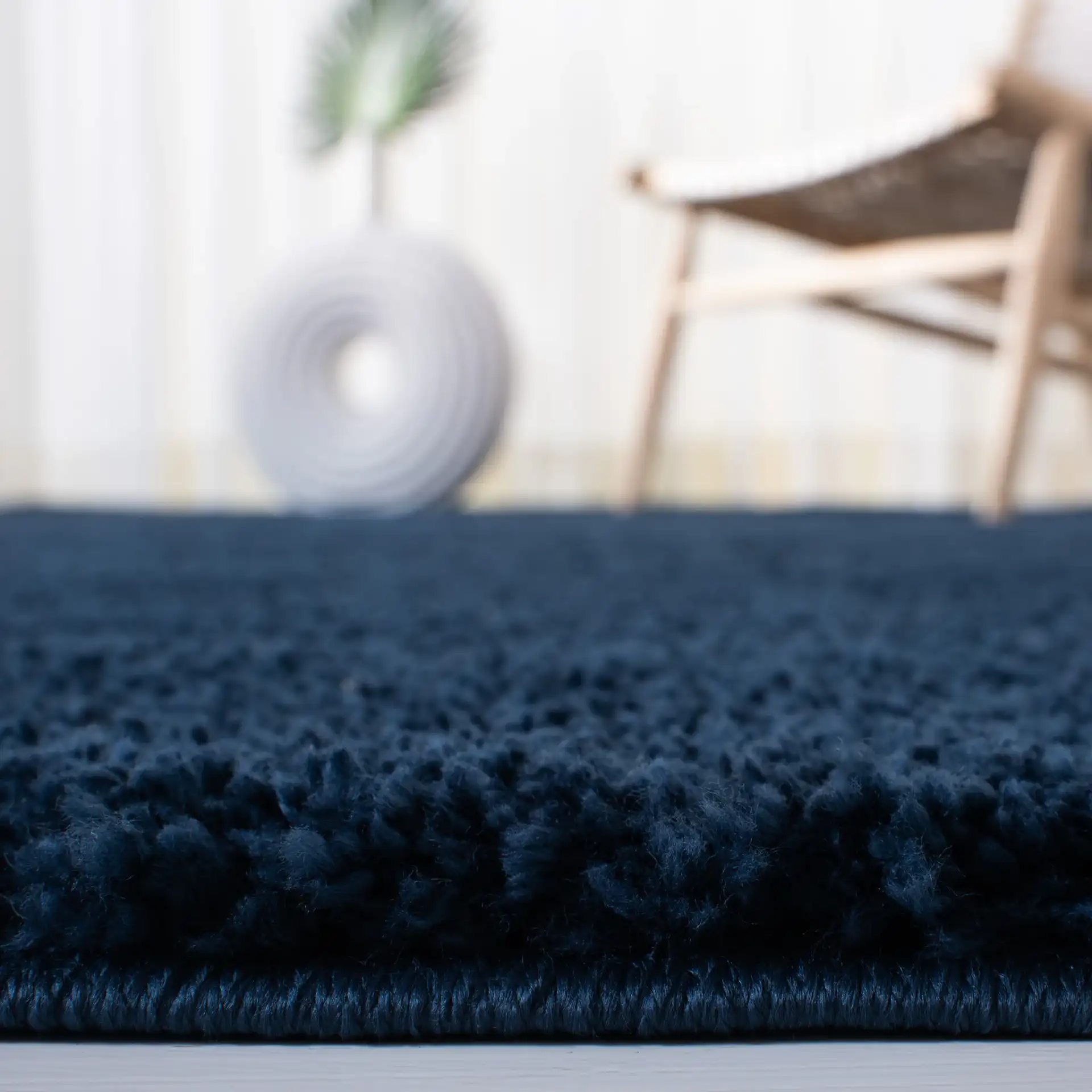 August Solid Shag Rug in Navy in a styled room