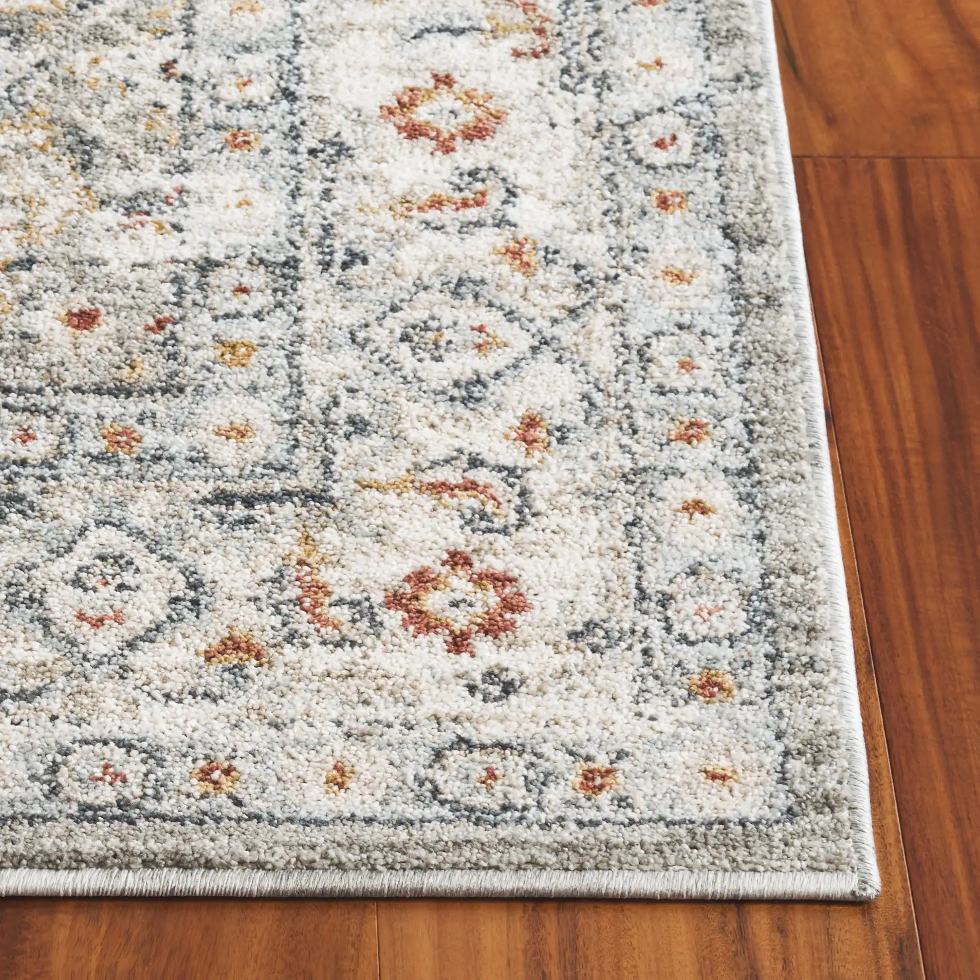 Avalon Floral Bordered Rug in Gray / Light Blue in a styled room