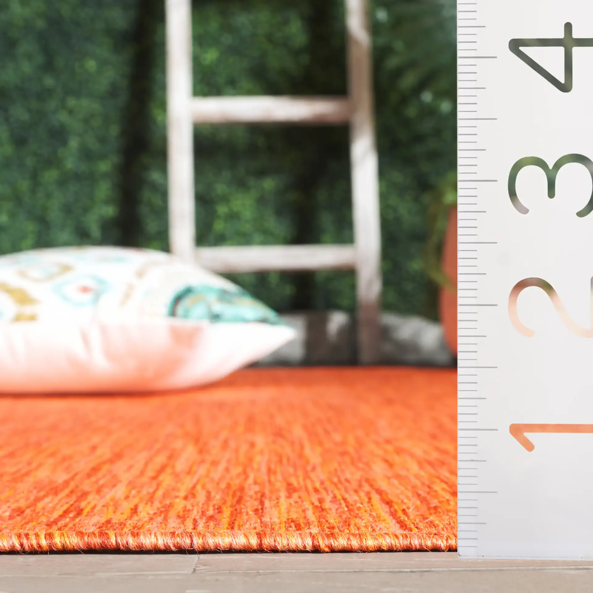 Beach House Textured Solid Outdoor Rug in Orange in a styled room