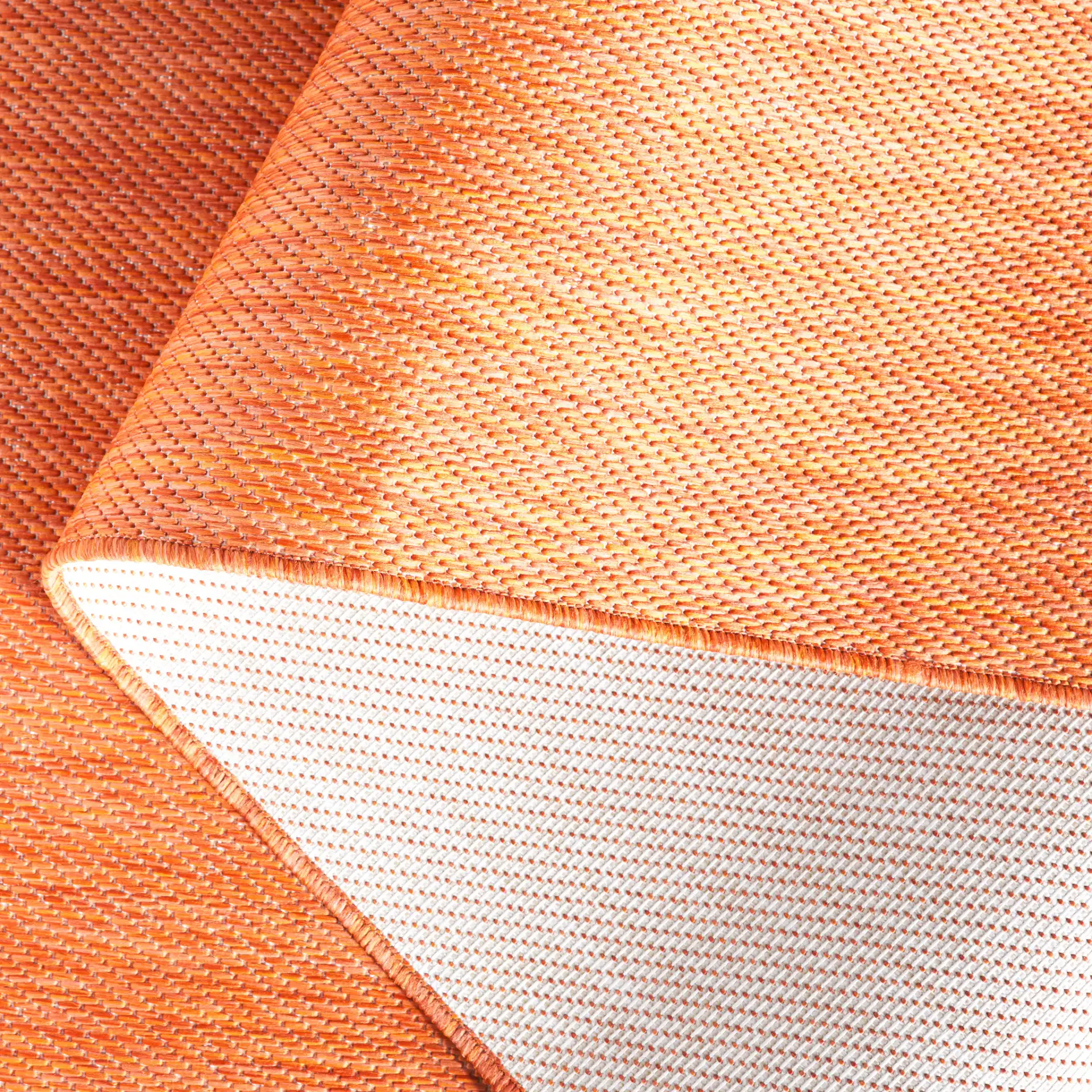 Beach House Textured Solid Outdoor Rug in Orange in a styled room