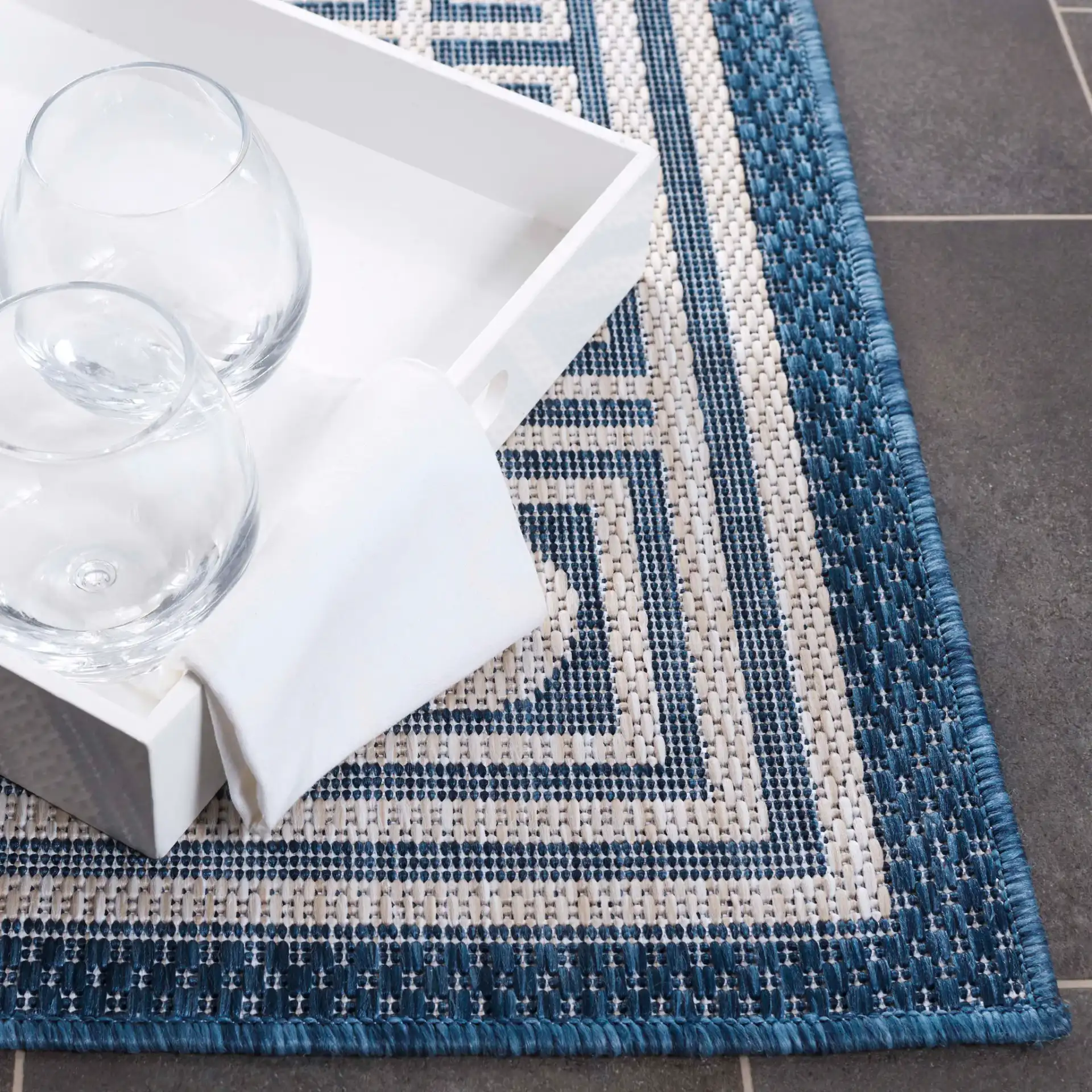 Beach House Greek Key Border Outdoor Rug in Blue / Ivory in a styled room