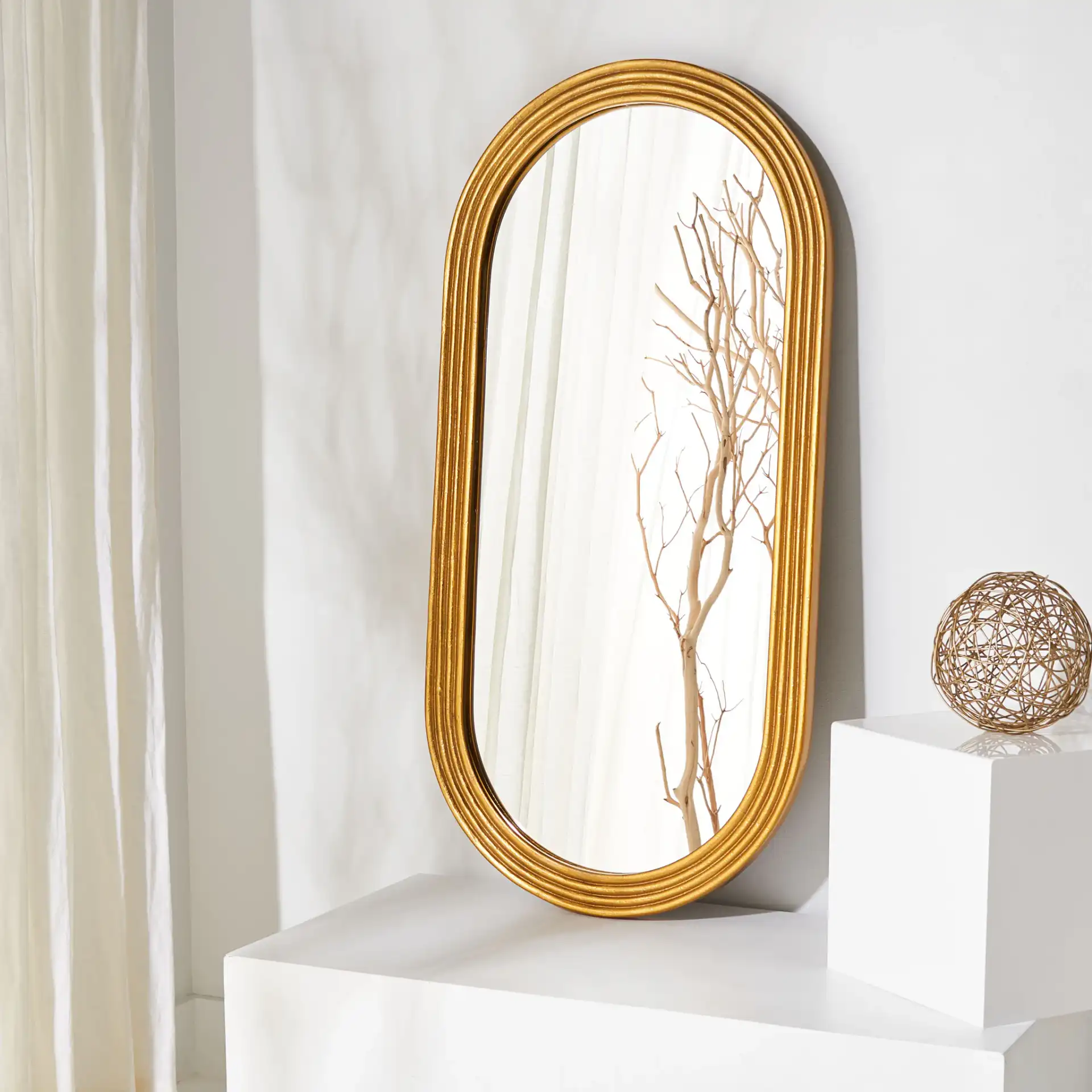 Jeanelle Oval Gold Mirror in Gold in a styled room