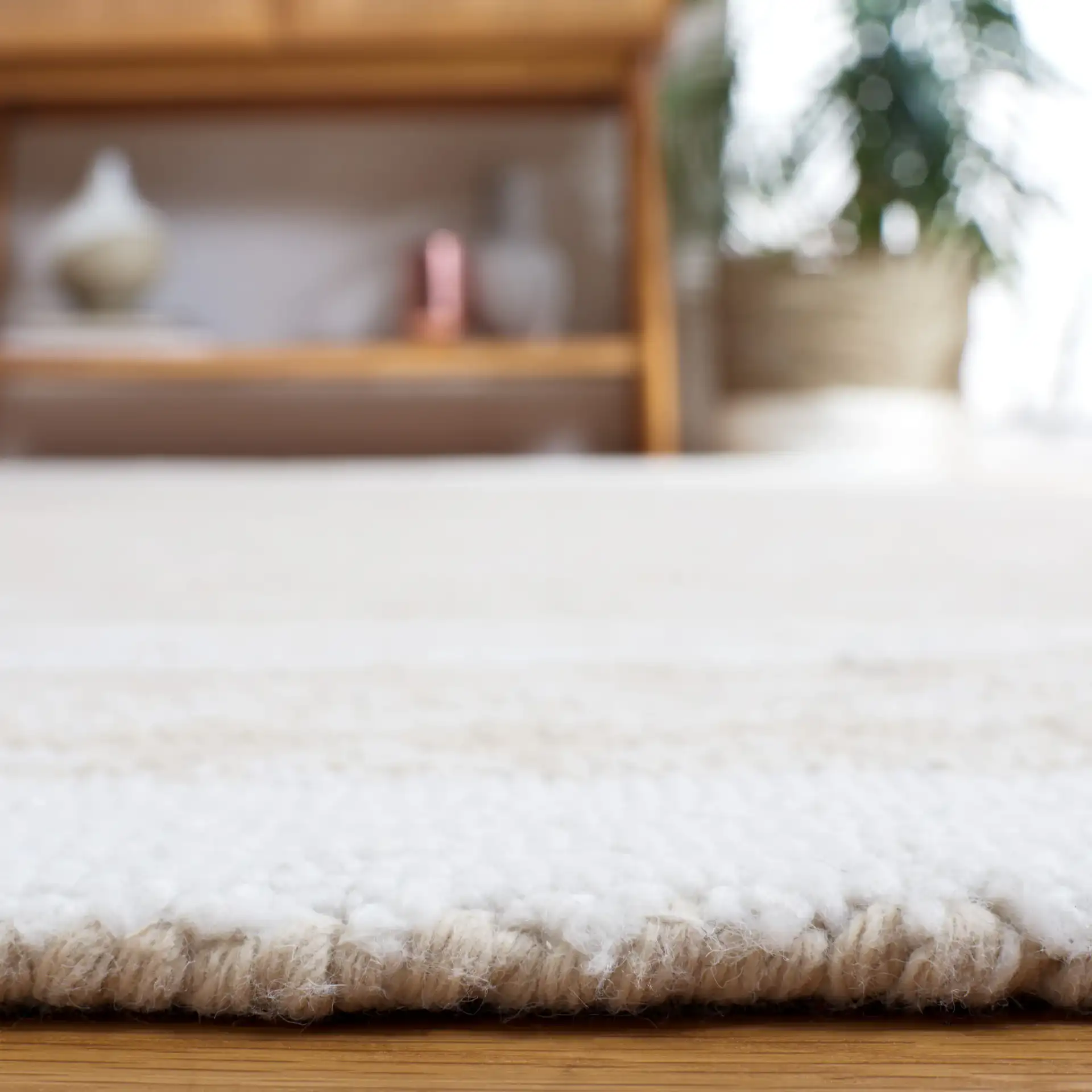 Capri Solid Bordered Hand-Tufted Rug in Ivory / Beige in a styled room