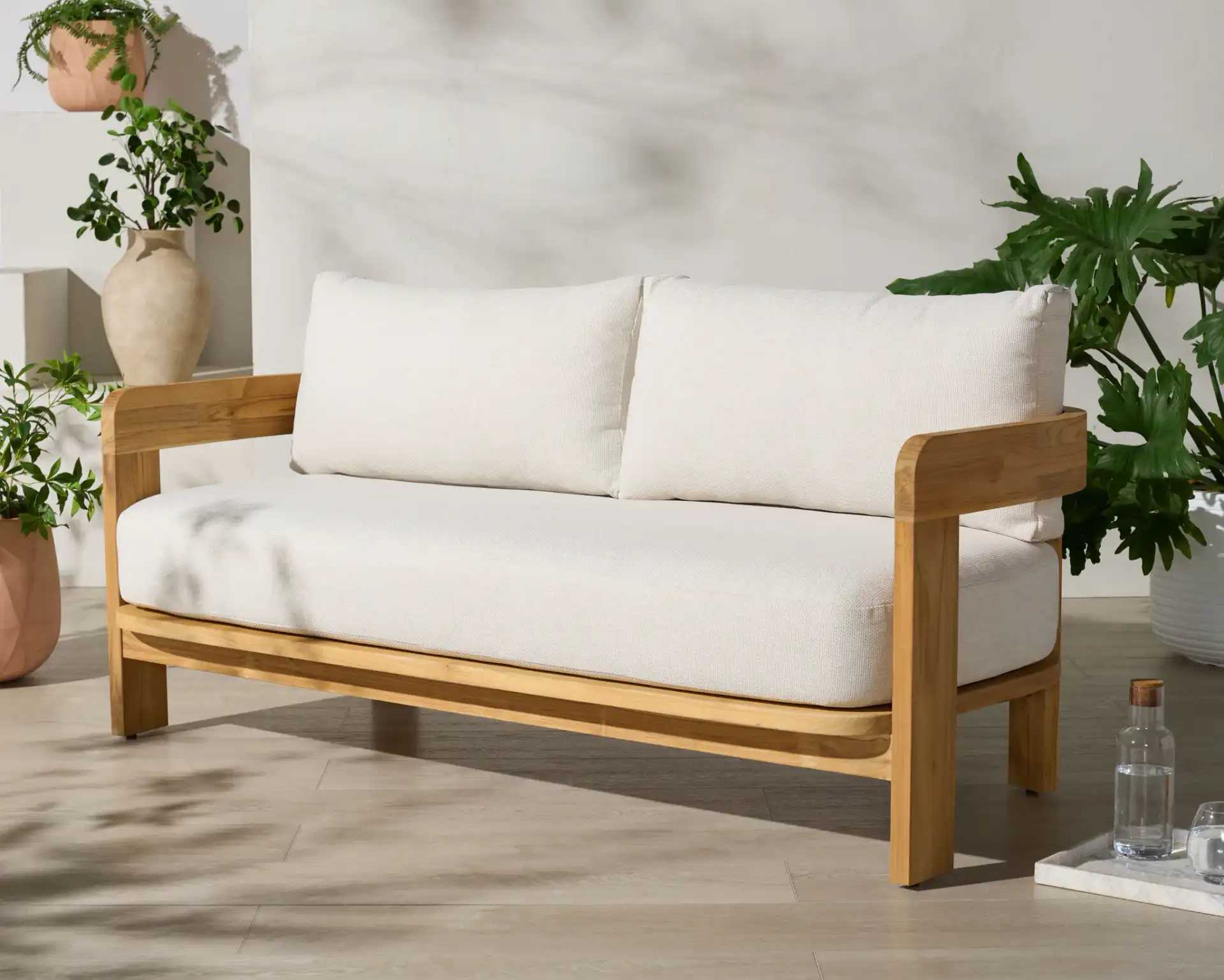 Achilles Teak Patio Sofa in White / Natural Teak in a styled room