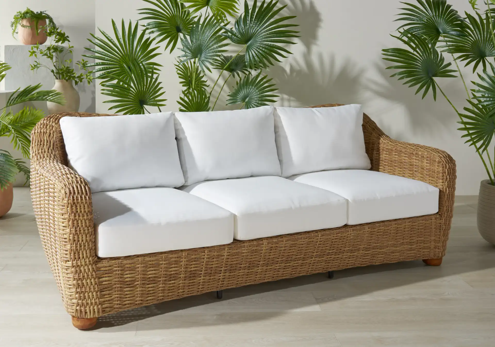 Melbourne Wicker Patio Sofa in Natural / White in a styled room