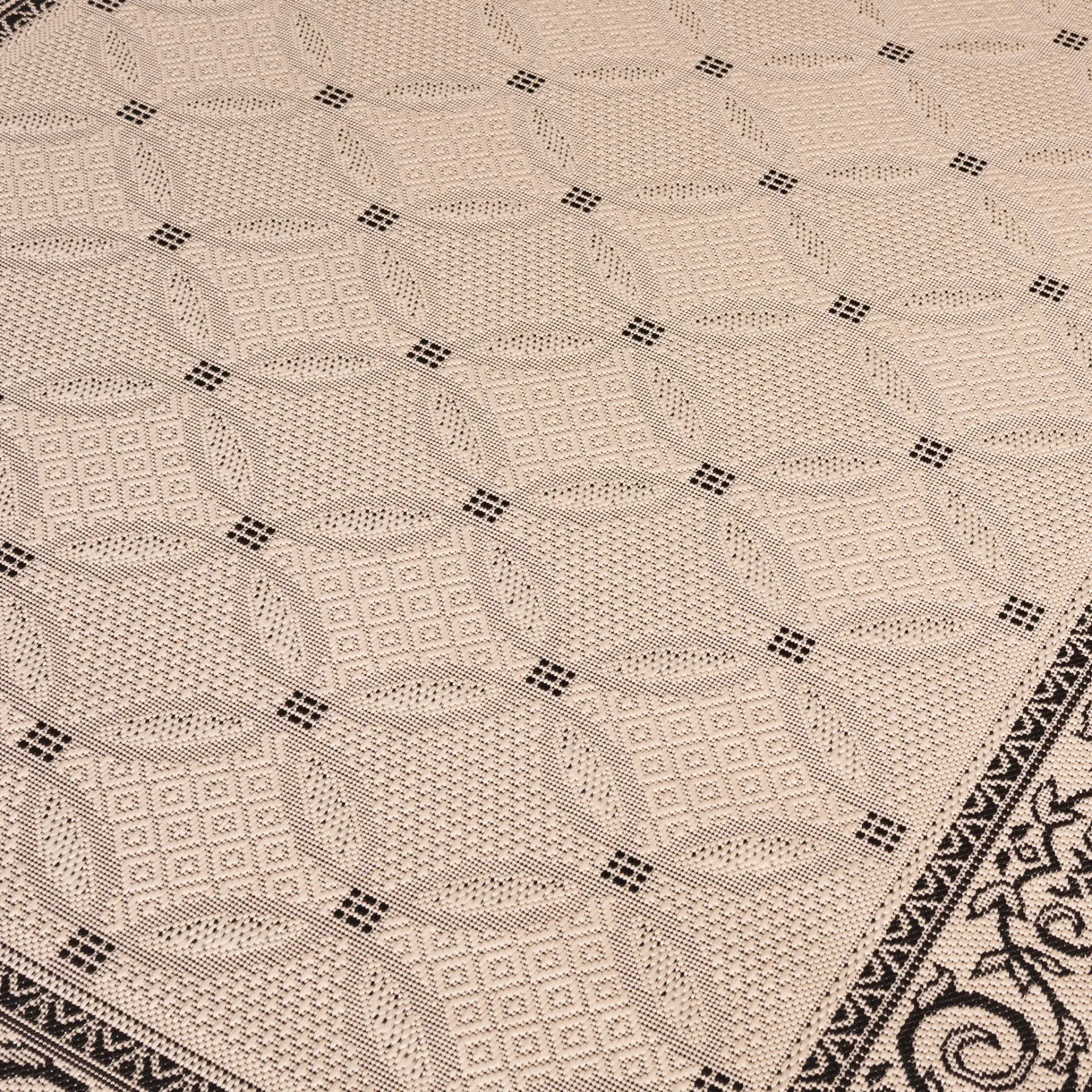Courtyard Interlocking Ring Bordered Outdoor Rug in Sand / Black in a styled room