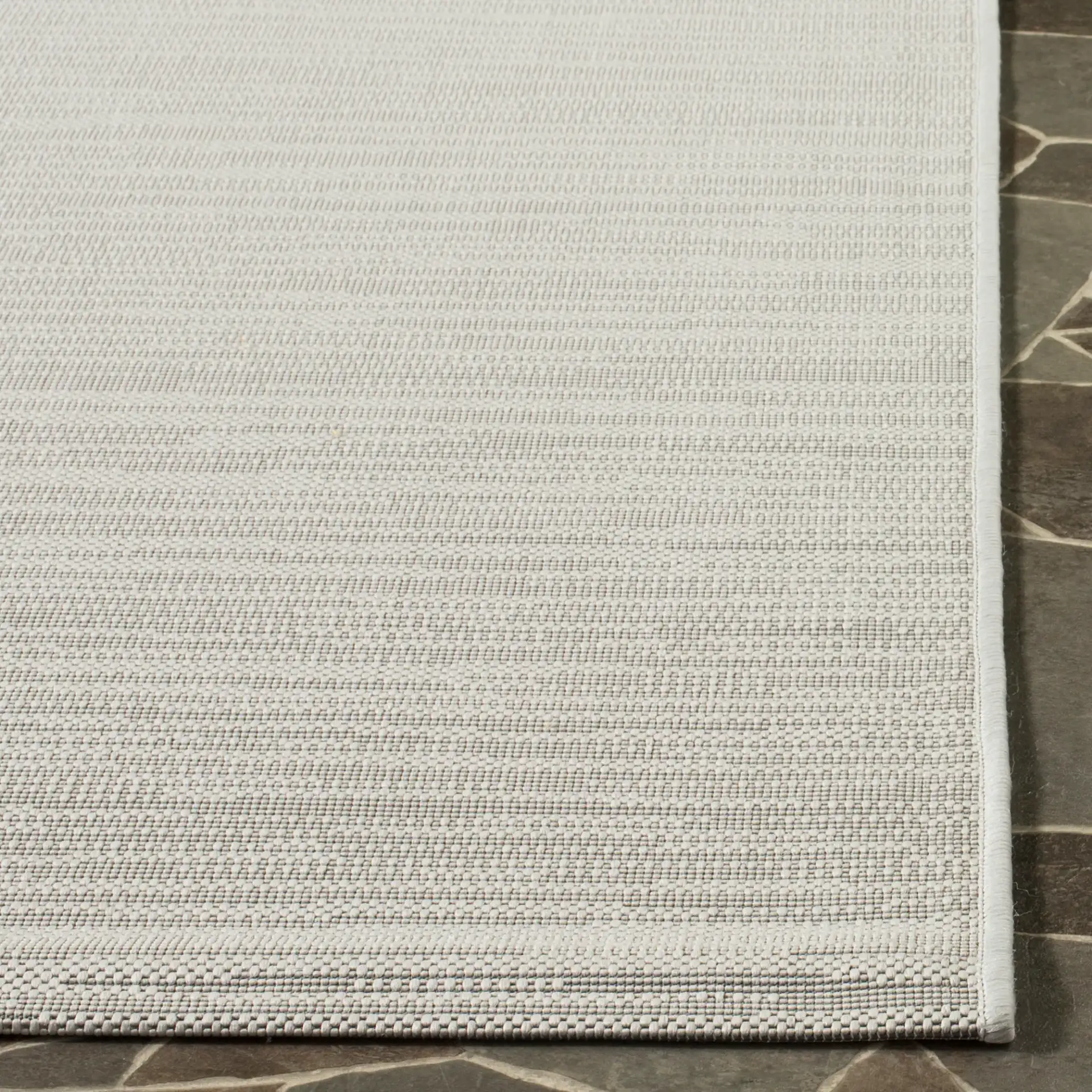 Courtyard Textured Solid Outdoor Rug in Light Gray in a styled room