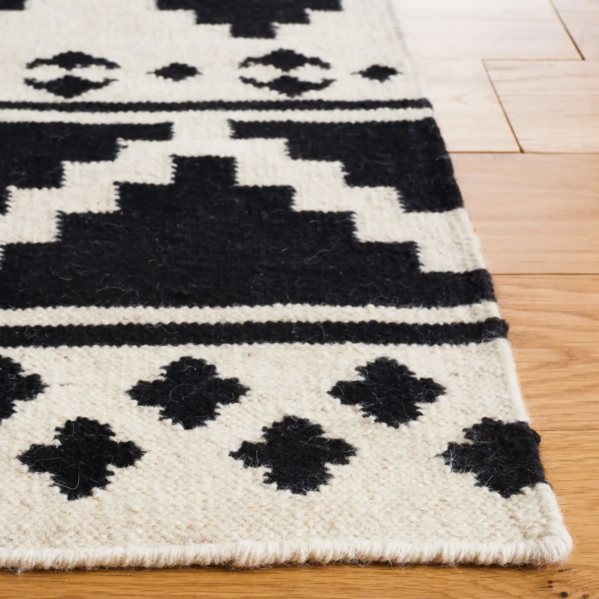 Dhurries Banded Geometric Hand-Woven Wool Rug in Black / Ivory in a styled room