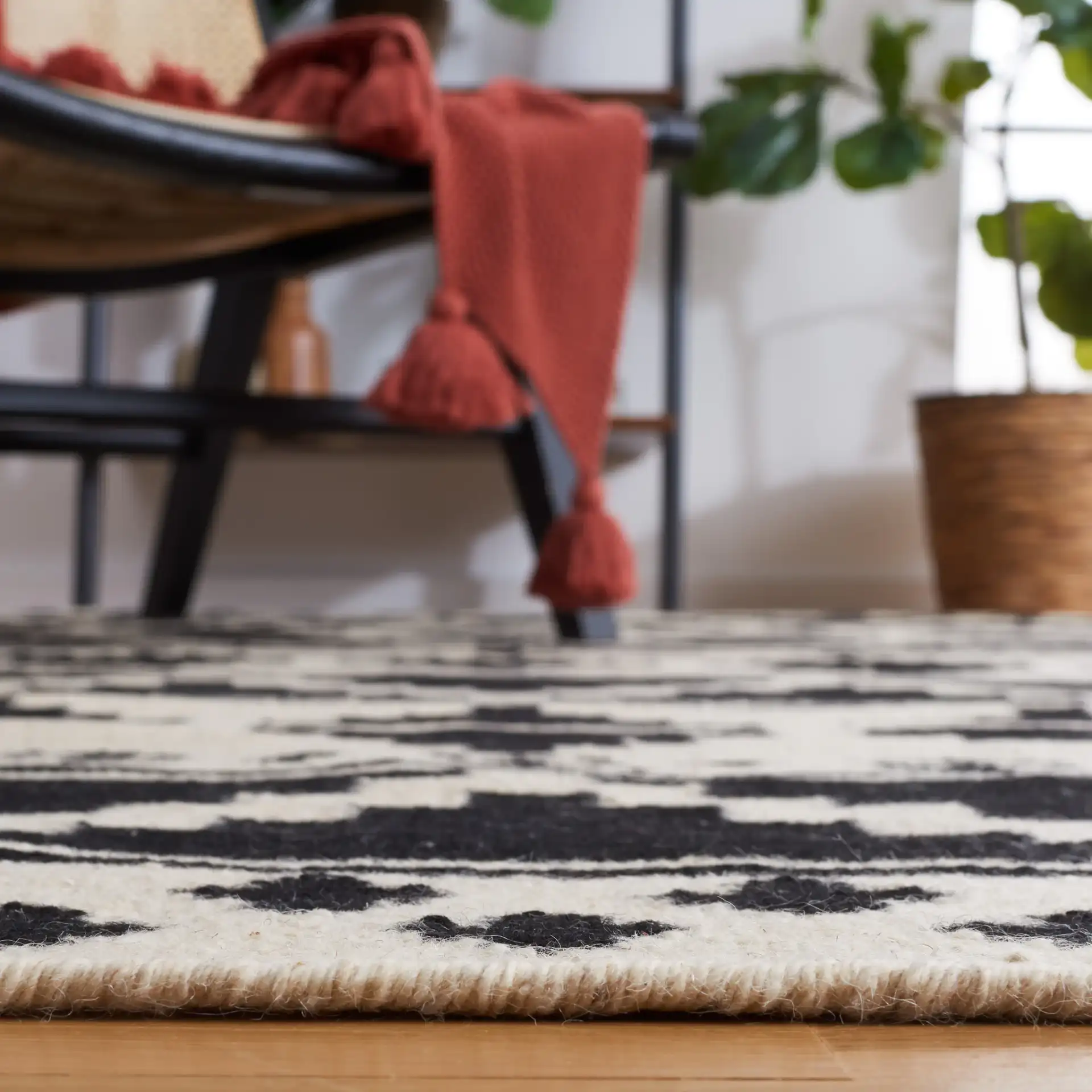 Dhurries Banded Geometric Hand-Woven Wool Rug in Black / Ivory in a styled room