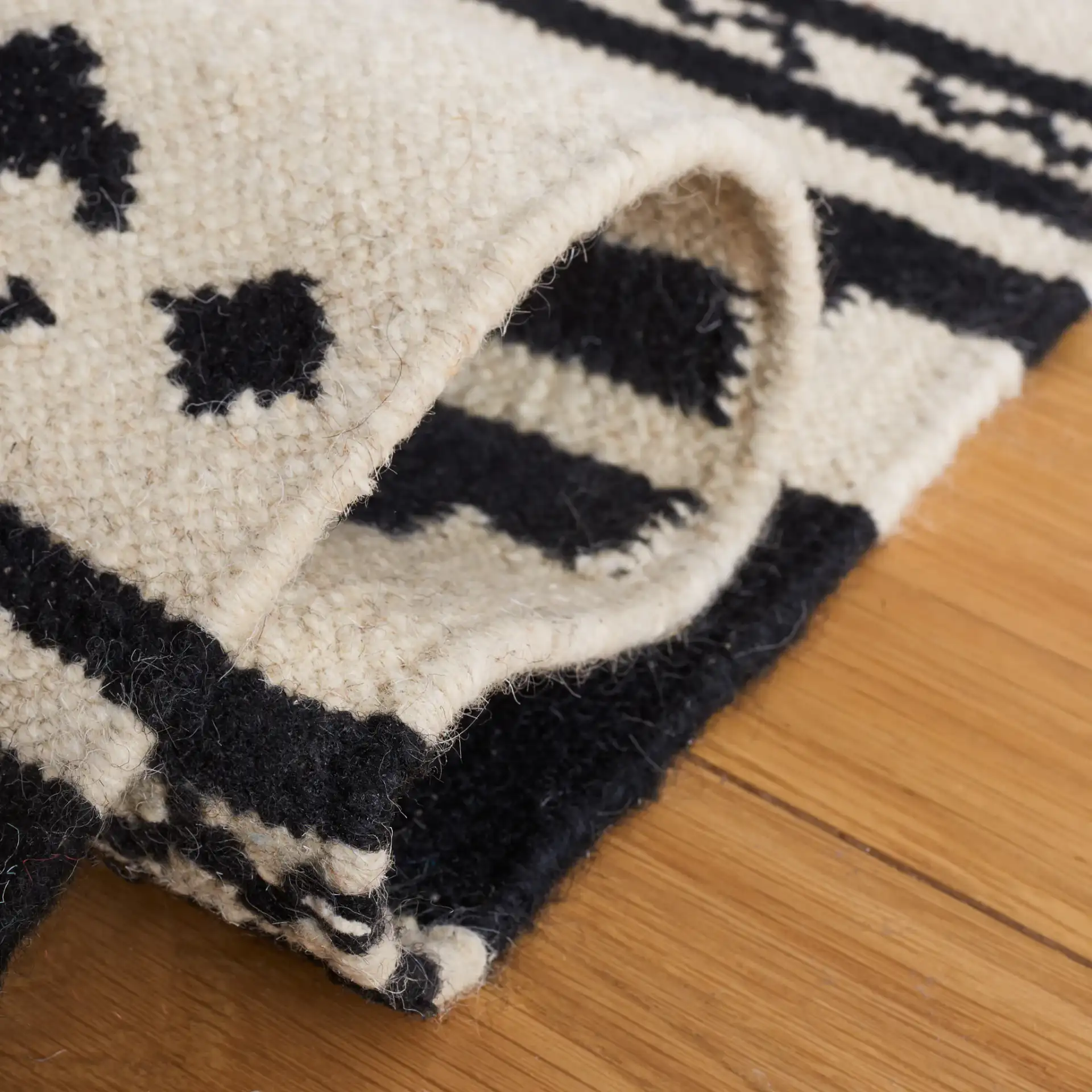 Dhurries Banded Geometric Hand-Woven Wool Rug in Black / Ivory in a styled room