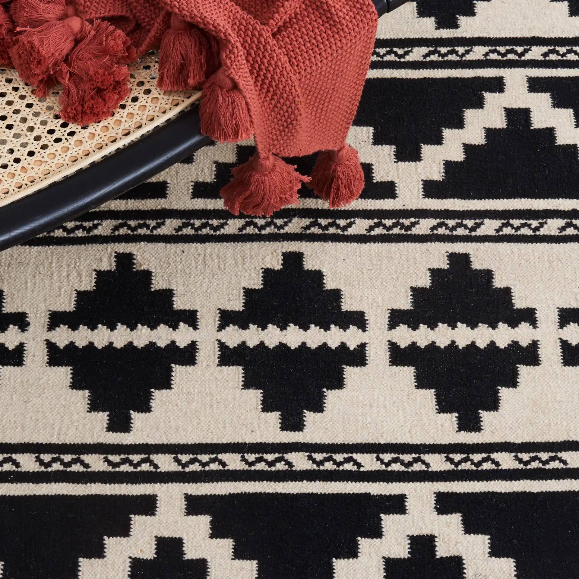 Dhurries Banded Geometric Hand-Woven Wool Rug in Black / Ivory in a styled room