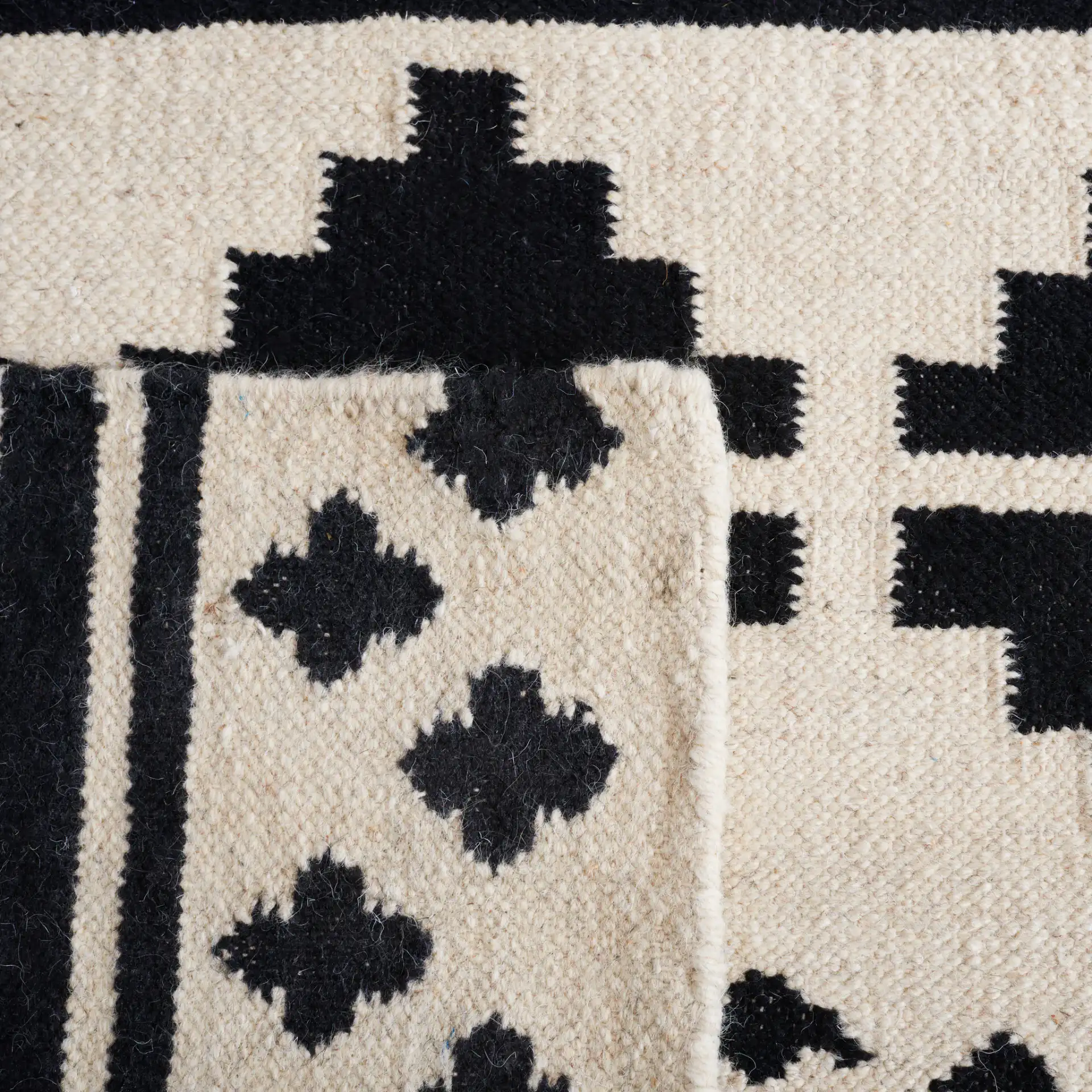 Dhurries Banded Geometric Hand-Woven Wool Rug in Black / Ivory in a styled room