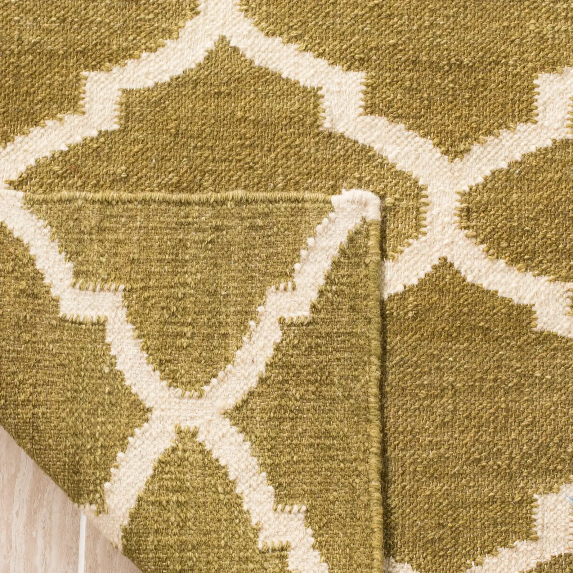 Dhurries Ogee Trellis Hand-Woven Wool Rug in Green / Ivory in a styled room