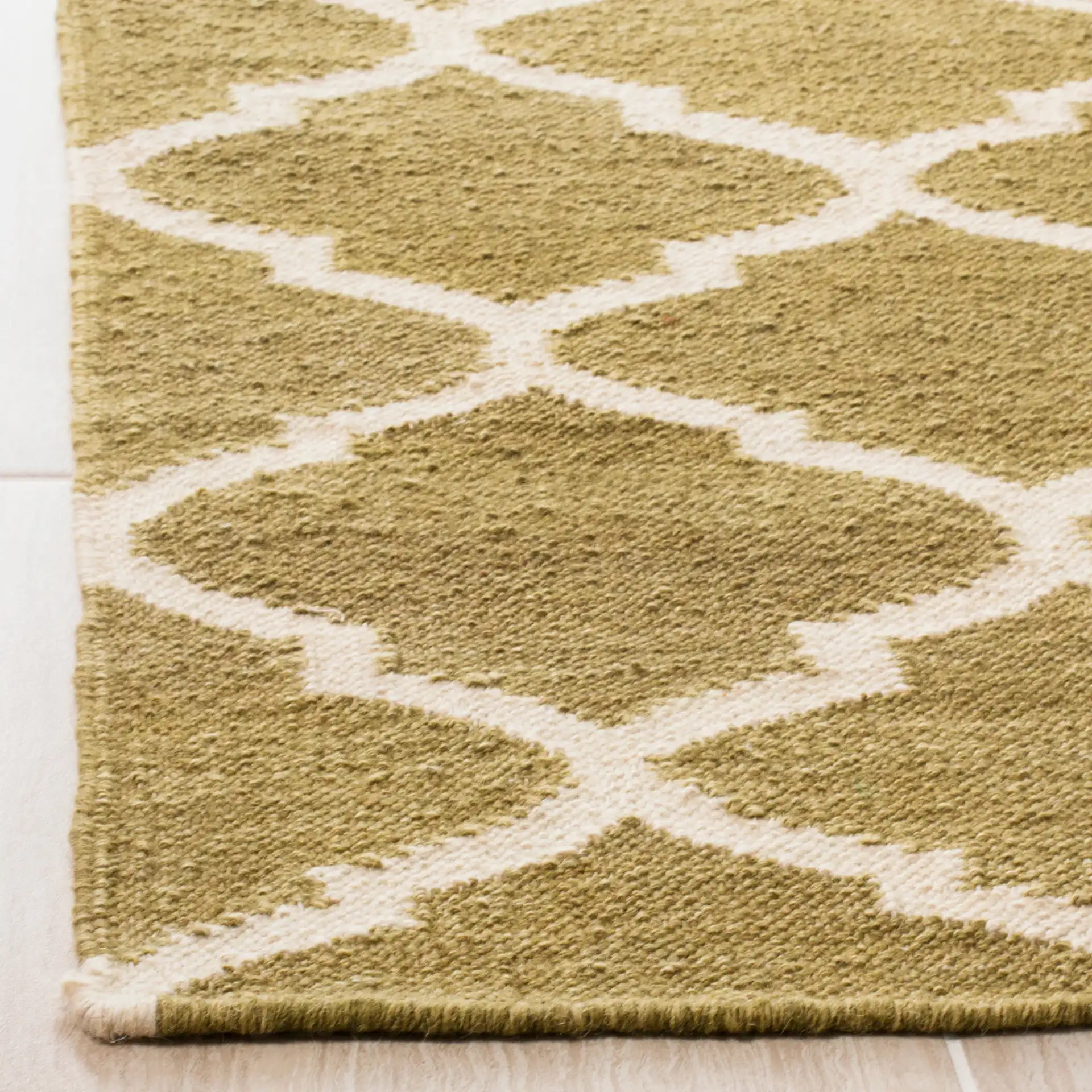 Dhurries Ogee Trellis Hand-Woven Wool Rug in Green / Ivory in a styled room