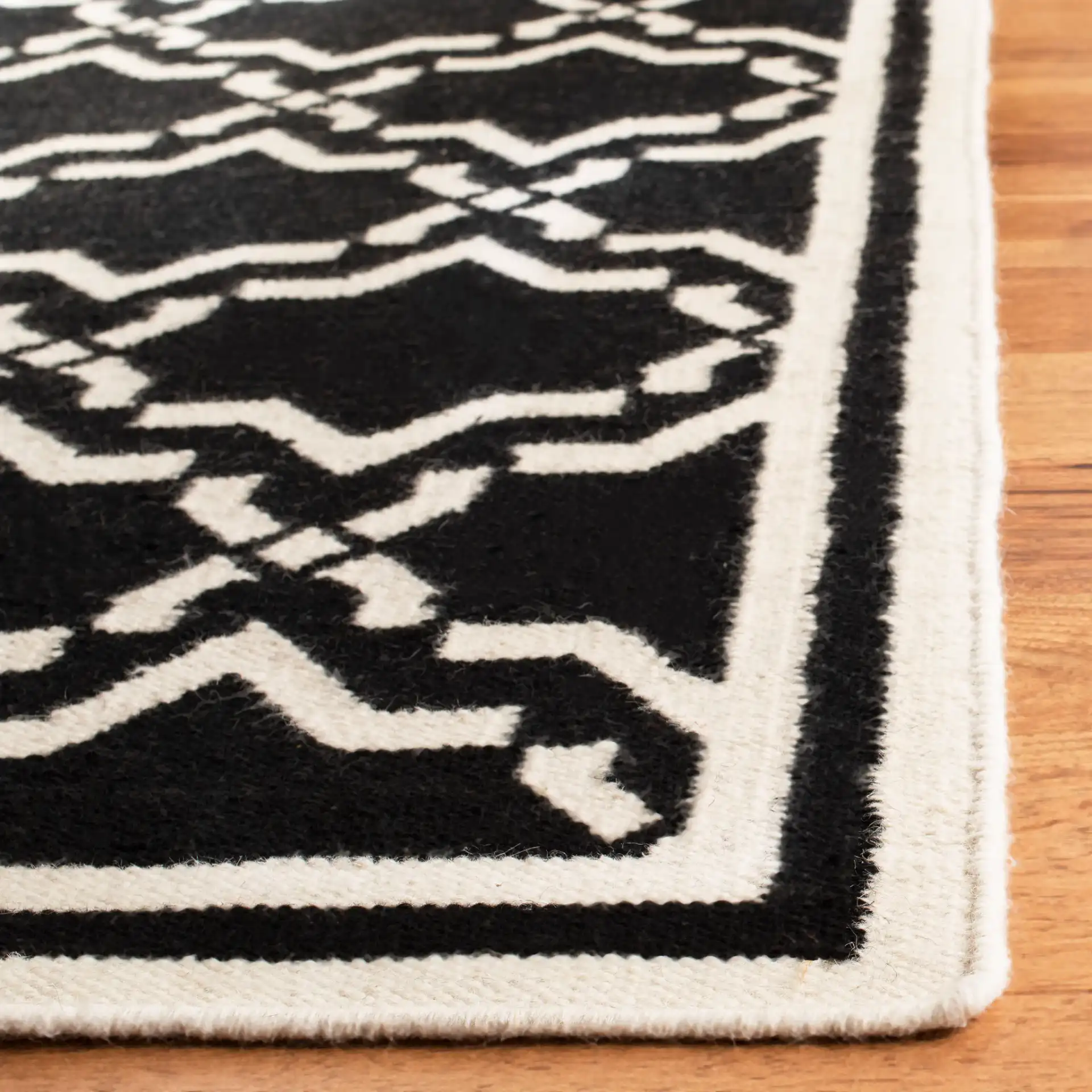 Dhurries Bordered Geometric Trellis Hand-Woven Rug in Black / Ivory in a styled room
