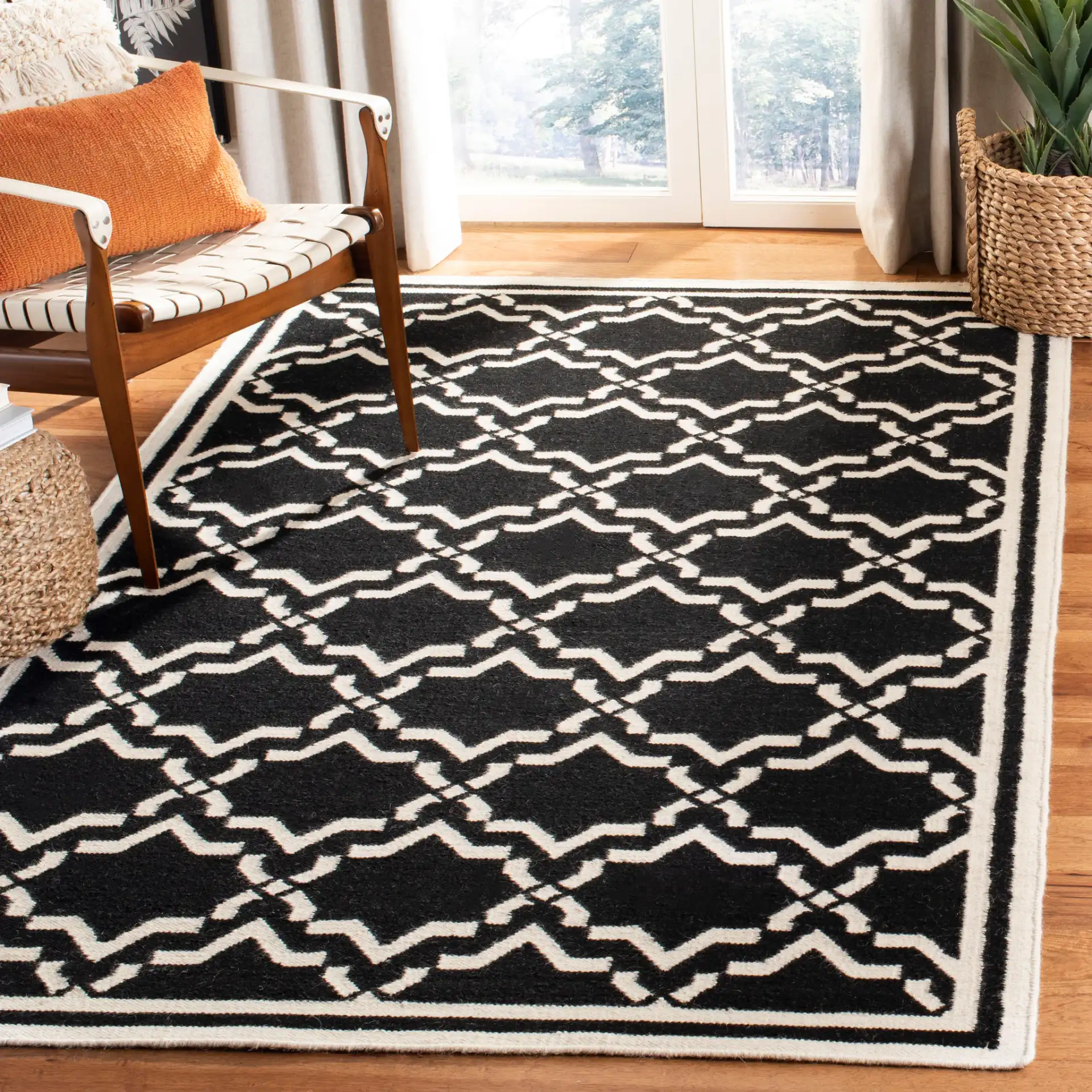 Dhurries Bordered Geometric Trellis Hand-Woven Rug in Black / Ivory in a styled room