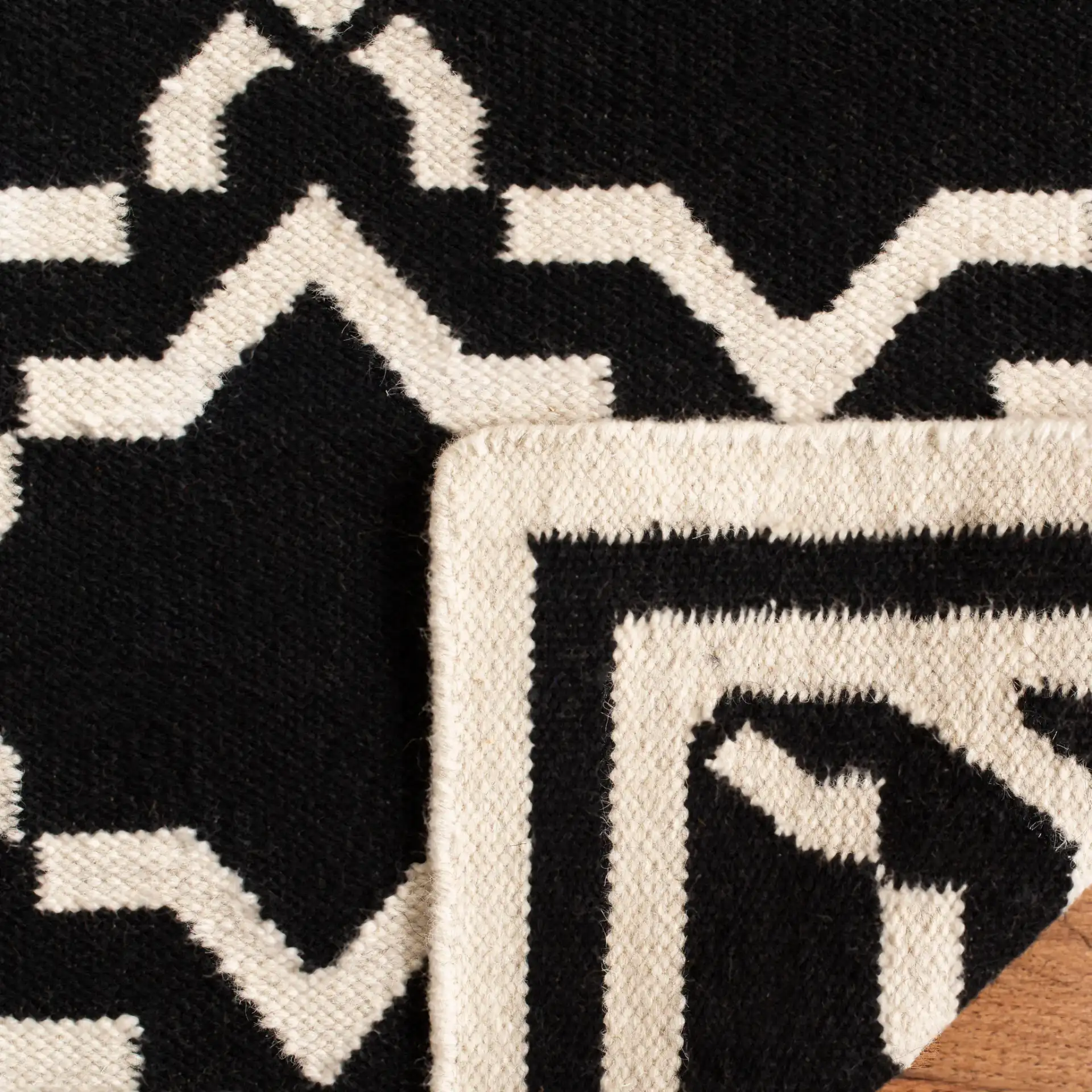 Dhurries Bordered Geometric Trellis Hand-Woven Rug in Black / Ivory in a styled room
