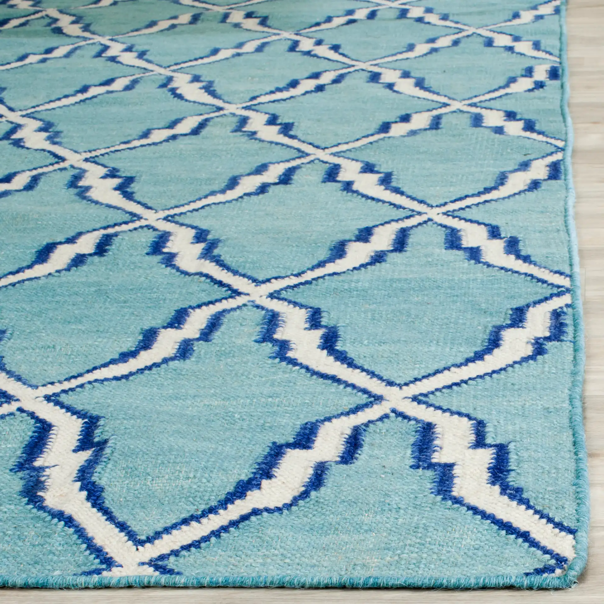 Dhurries Elongated Trellis Hand-Woven Rug in Light Blue / Ivory in a styled room