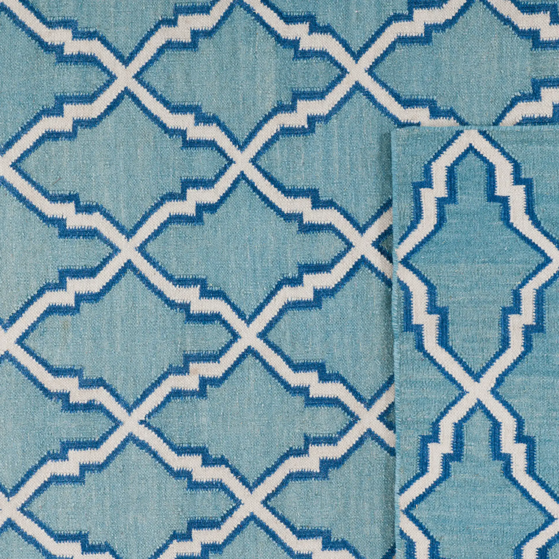 Dhurries Elongated Trellis Hand-Woven Rug in Light Blue / Ivory in a styled room