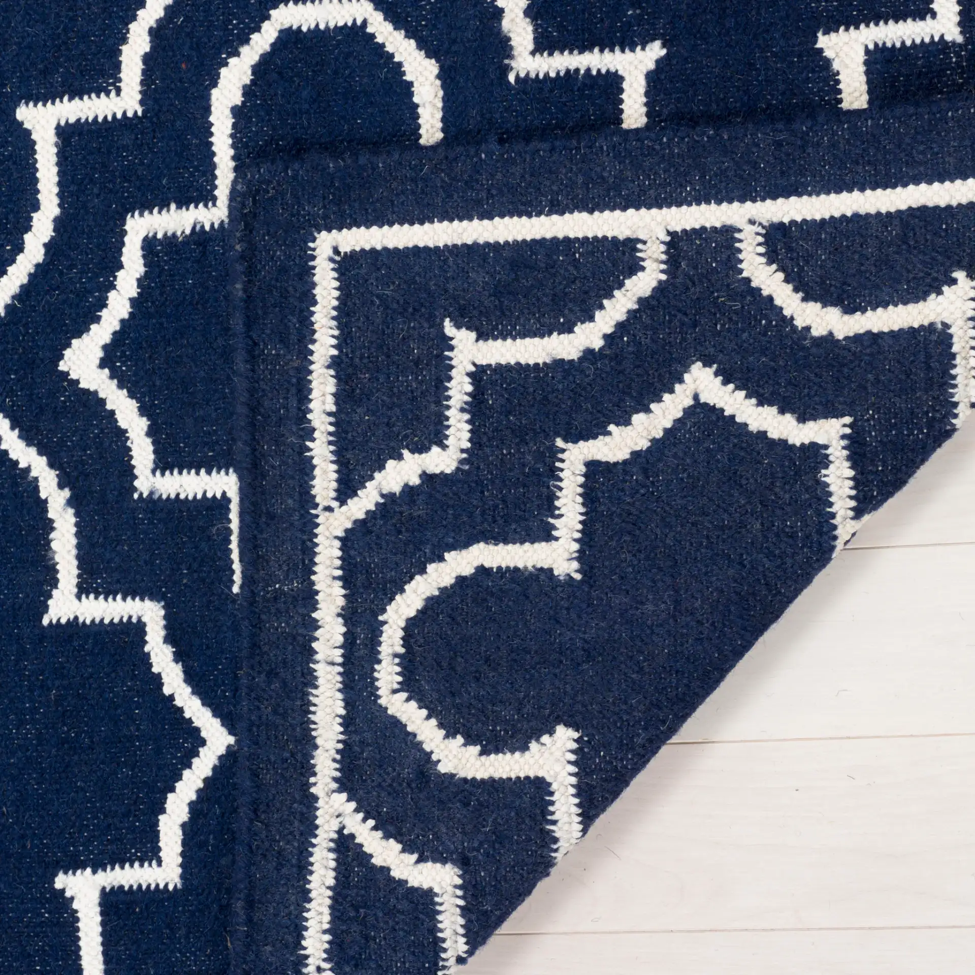 Dhurries Bordered Quatrefoil Hand-Woven Rug in Navy / Ivory in a styled room