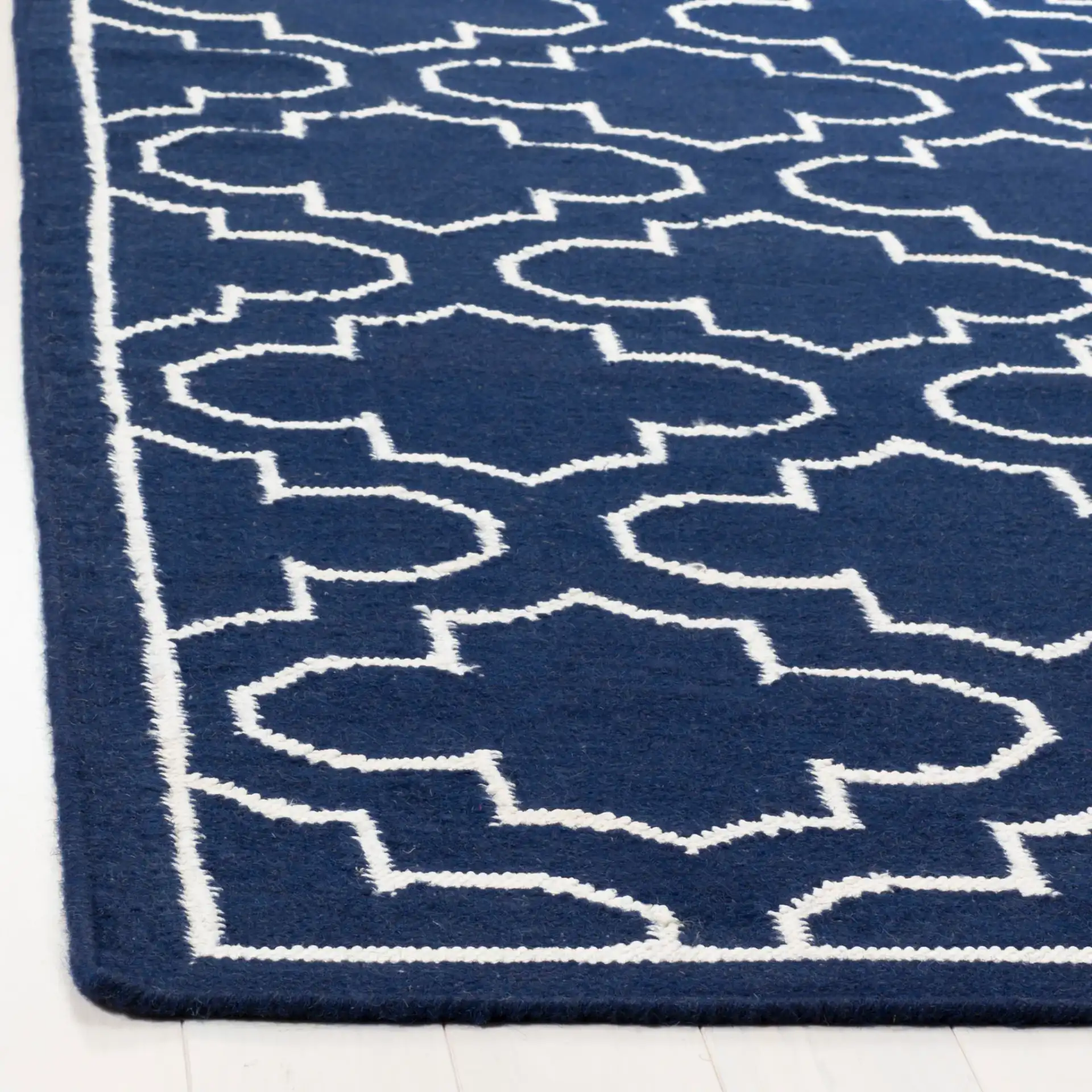 Dhurries Bordered Quatrefoil Hand-Woven Rug in Navy / Ivory in a styled room