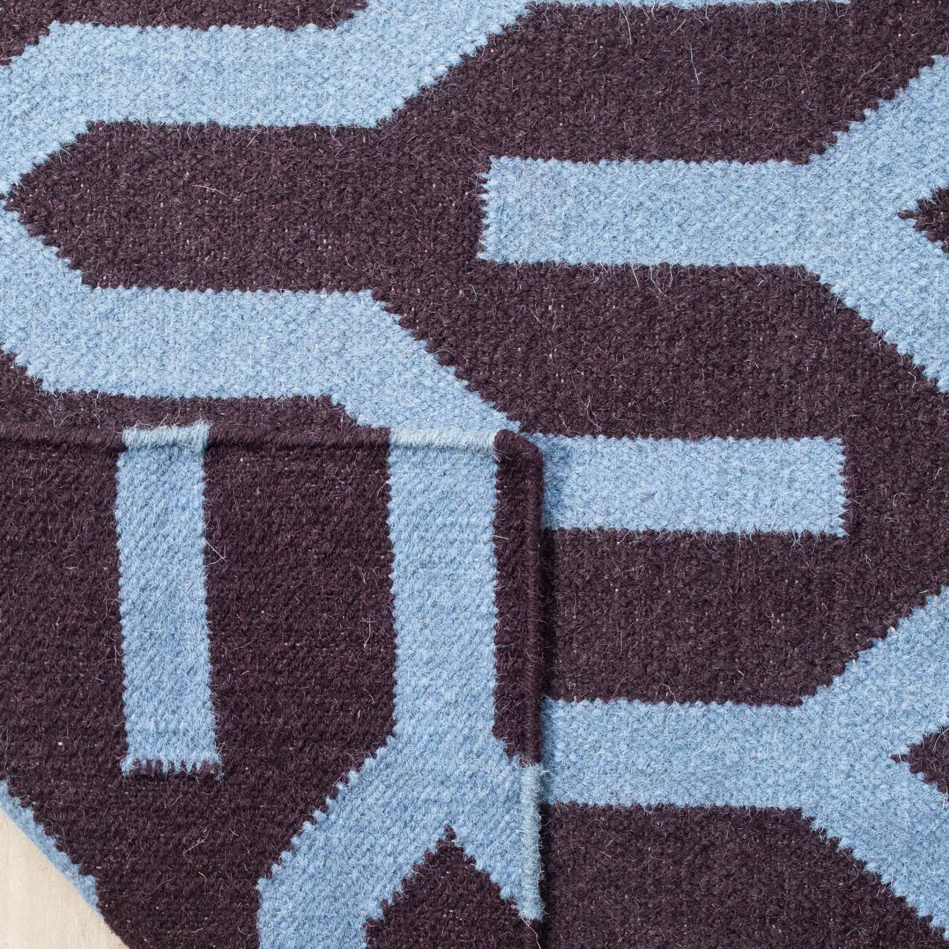Dhurries Interlocking Chevron Hand-Woven Wool Rug in Purple / Blue in a styled room