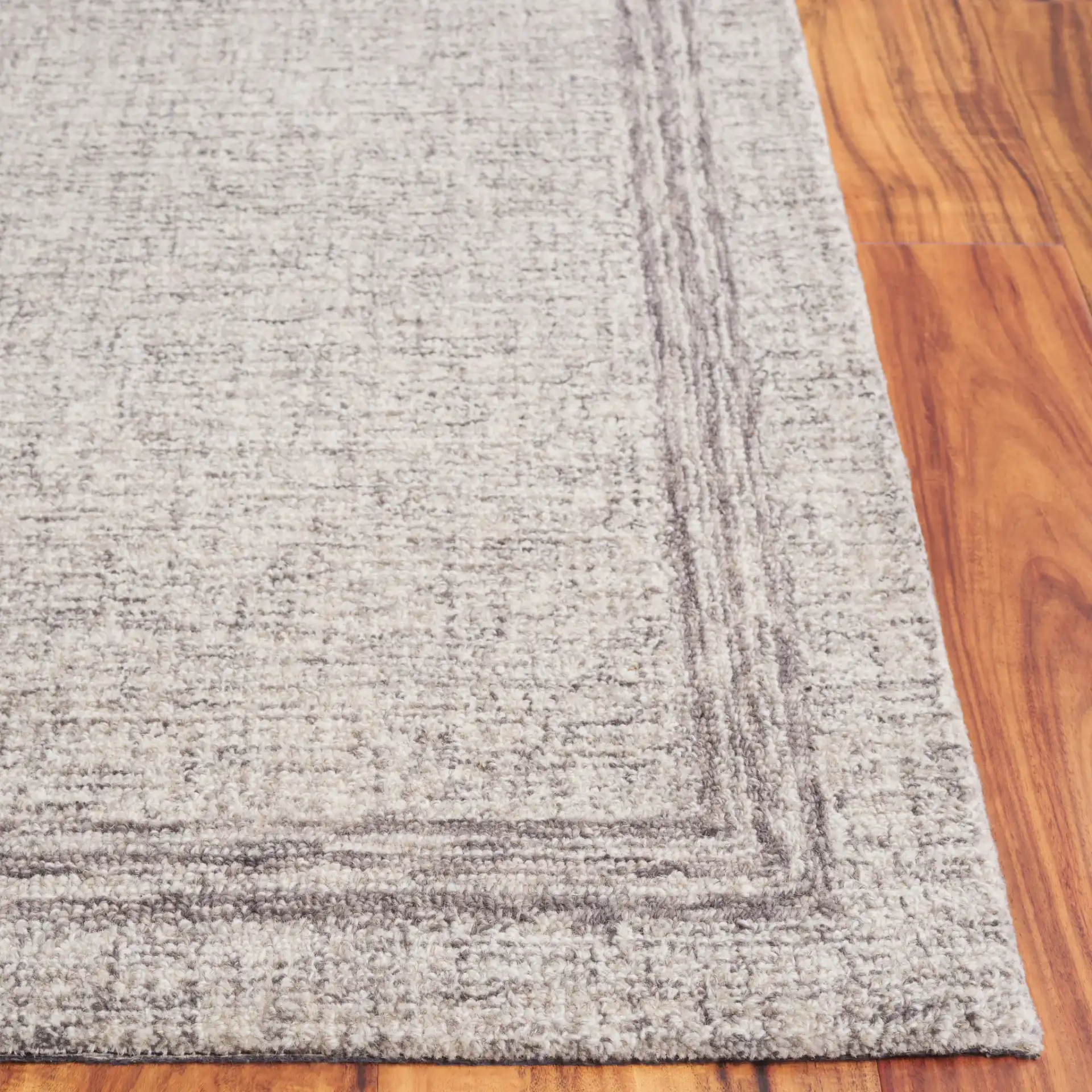 Ebony Bordered Hand-Tufted Wool Rug in Gray in a styled room