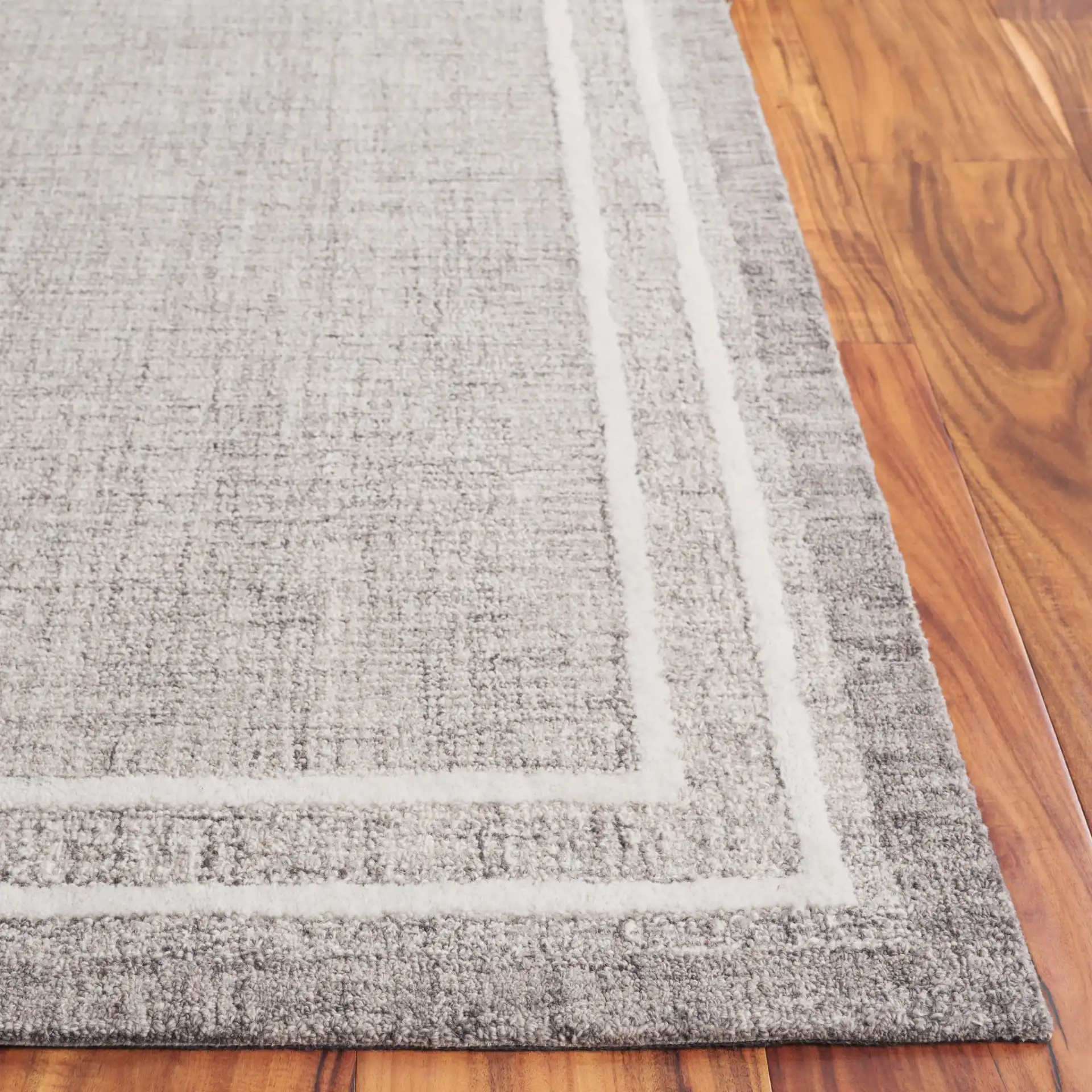 Ebony Concentric Border Hand-Tufted Wool Rug in Gray / Ivory in a styled room