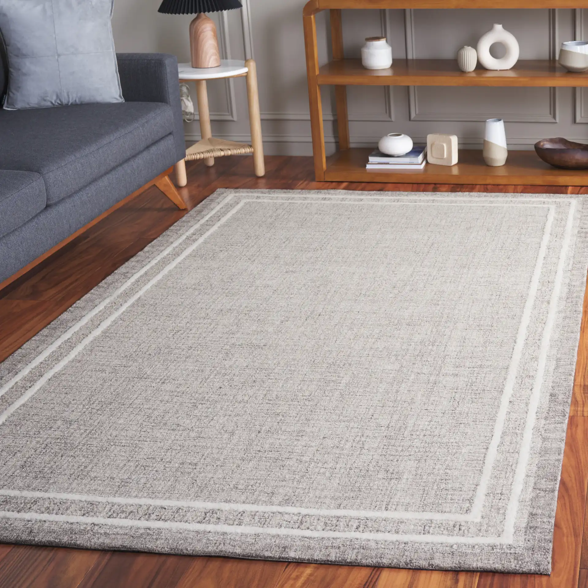 Ebony Concentric Border Hand-Tufted Wool Rug in Gray / Ivory in a styled room