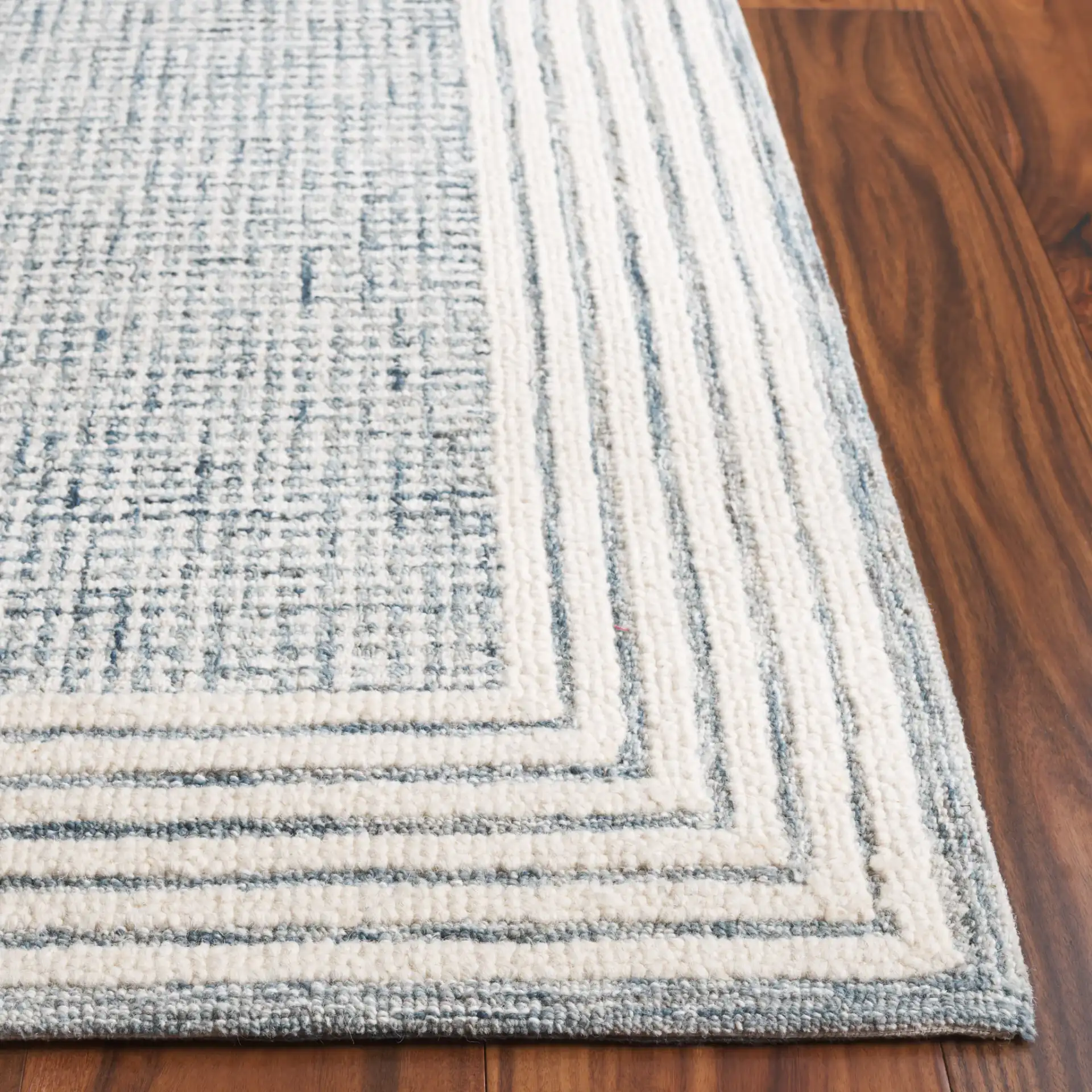 Ebony Grid Border Hand-Tufted Wool Rug in Blue / Ivory in a styled room