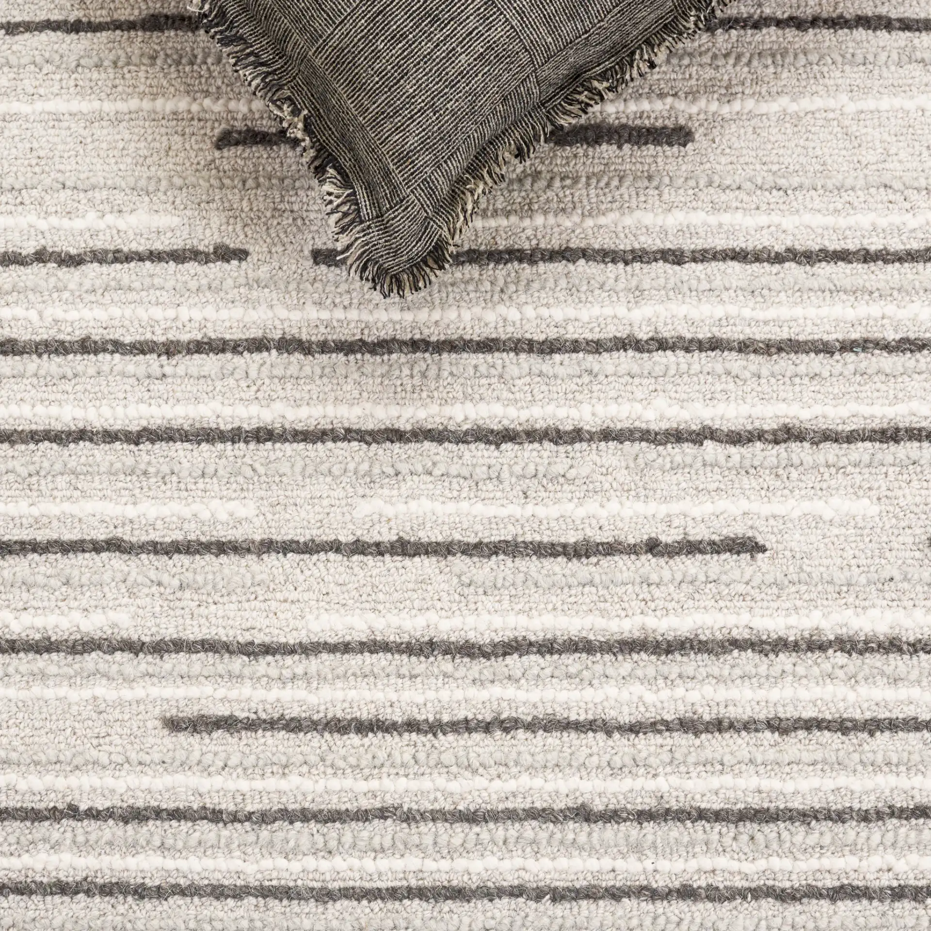 Ebony Dashed Stripe Hand-Tufted Wool Rug in Gray / Black in a styled room