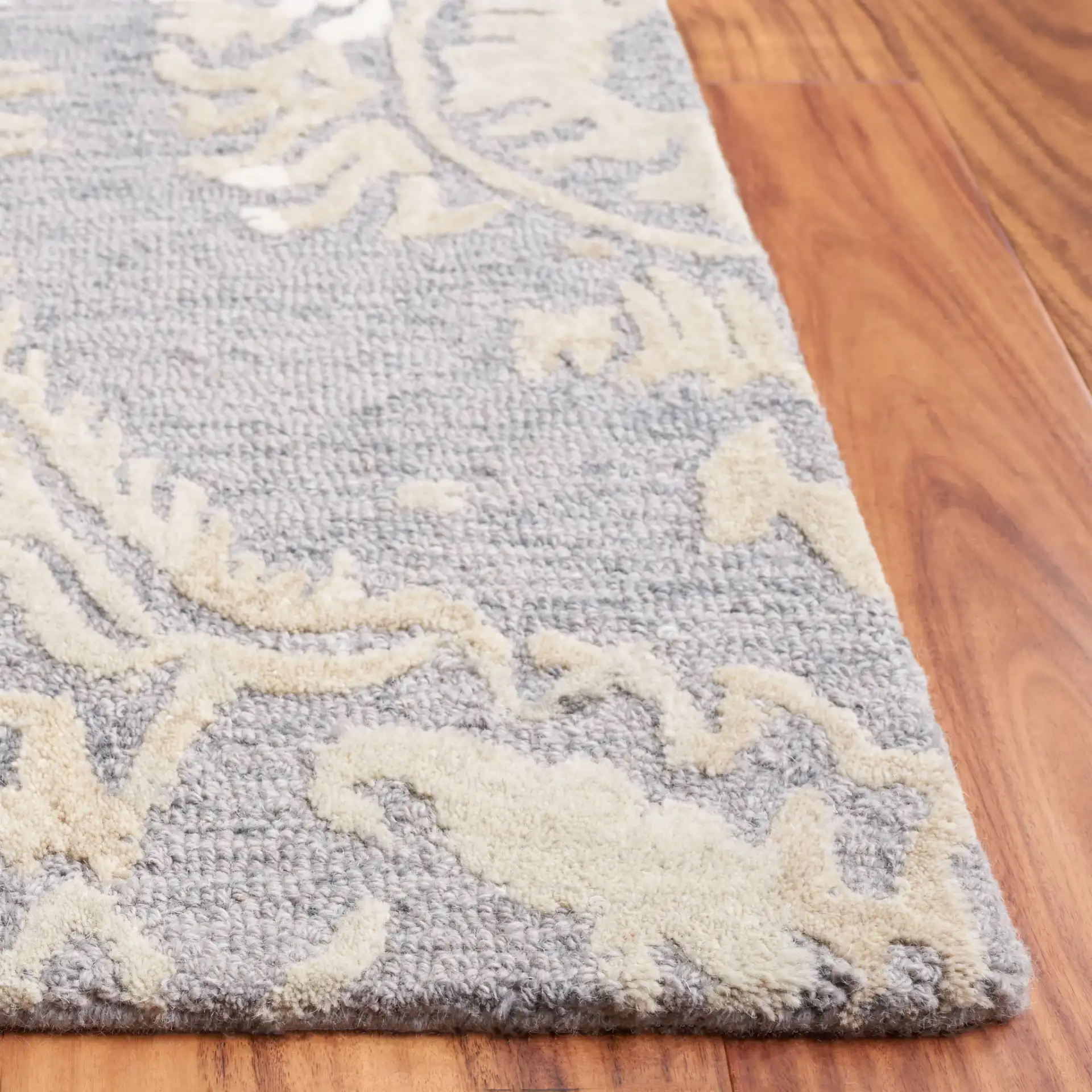 Ebony Scrolling Damask Hand-Tufted Wool Rug in Gray / Ivory in a styled room