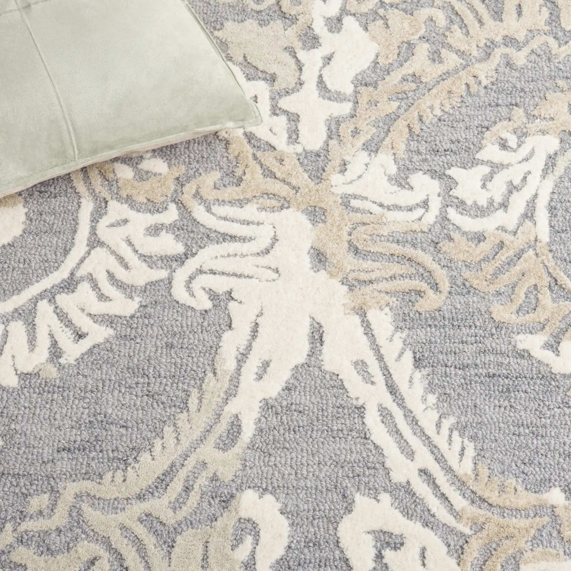 Ebony Scrolling Damask Hand-Tufted Wool Rug in Gray / Ivory in a styled room