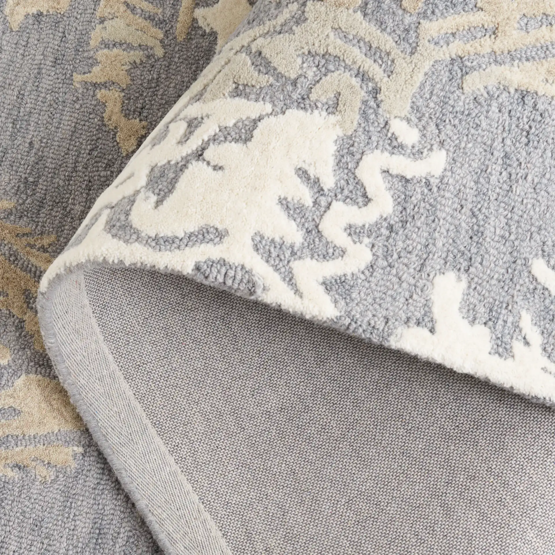 Ebony Scrolling Damask Hand-Tufted Wool Rug in Gray / Ivory in a styled room
