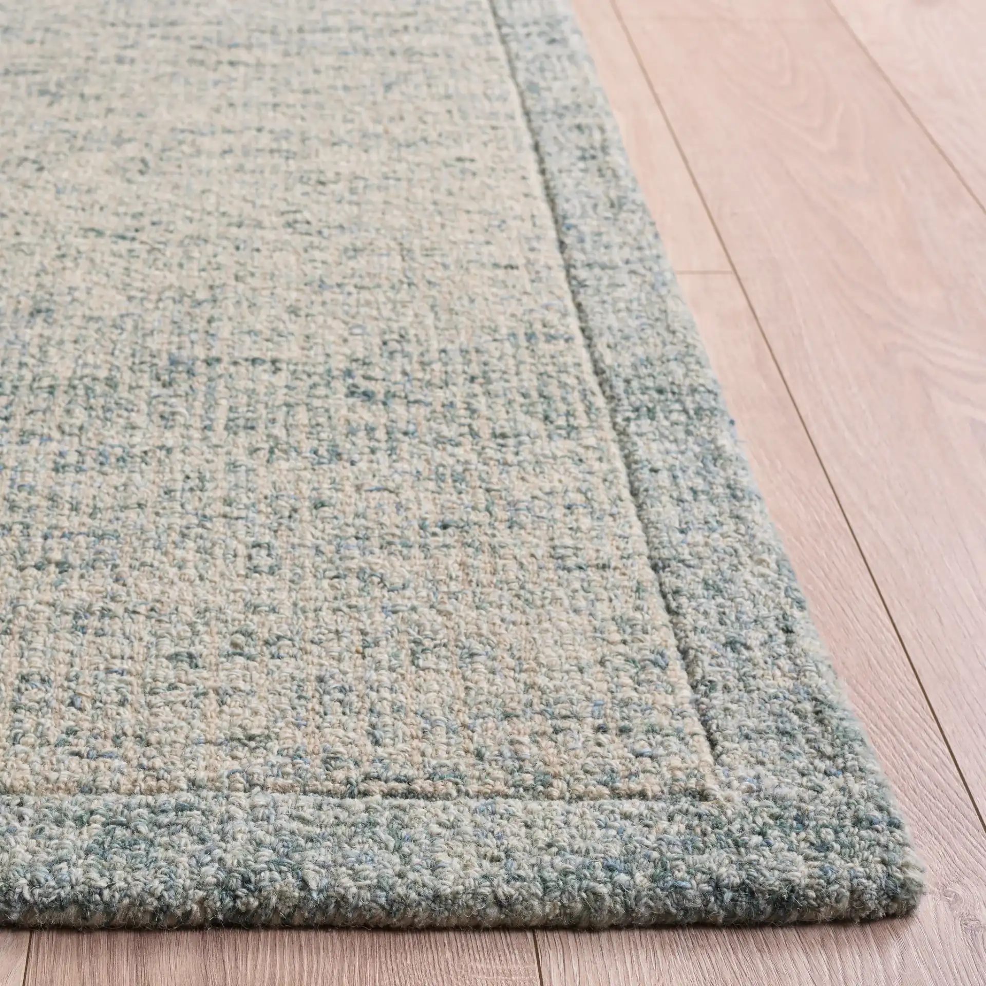 Ebony Bordered Solid Hand-Tufted Wool Rug in Light Blue in a styled room