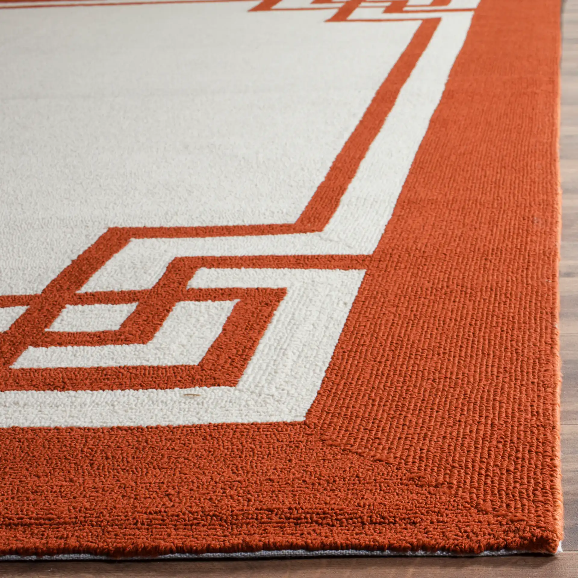 Four Seasons Greek Key Border Hand-Hooked Rug in Off-White / Sangria in a styled room