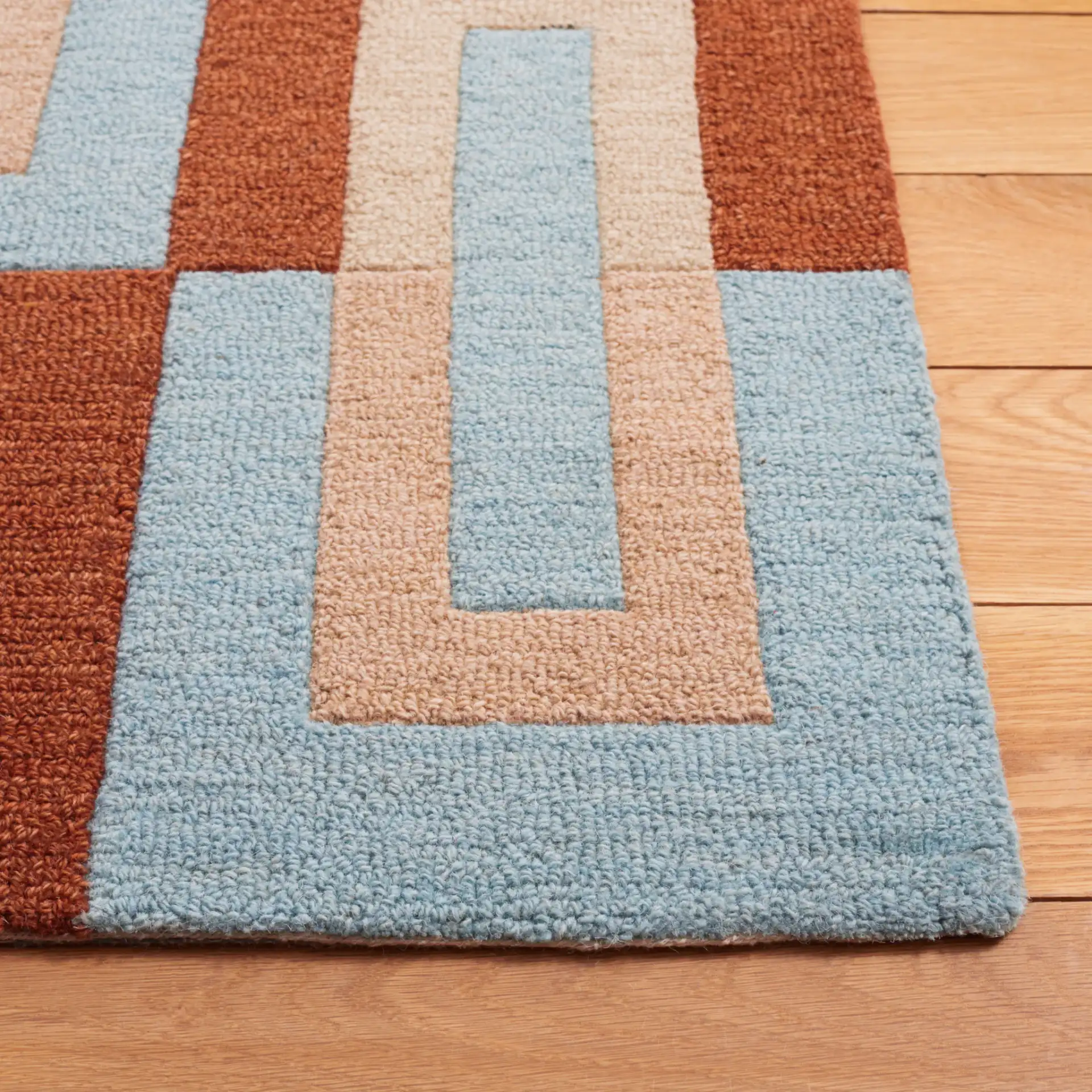 Genre Interlocking Rectangles Hand-Tufted Wool Rug in Light Blue / Rust in a styled room