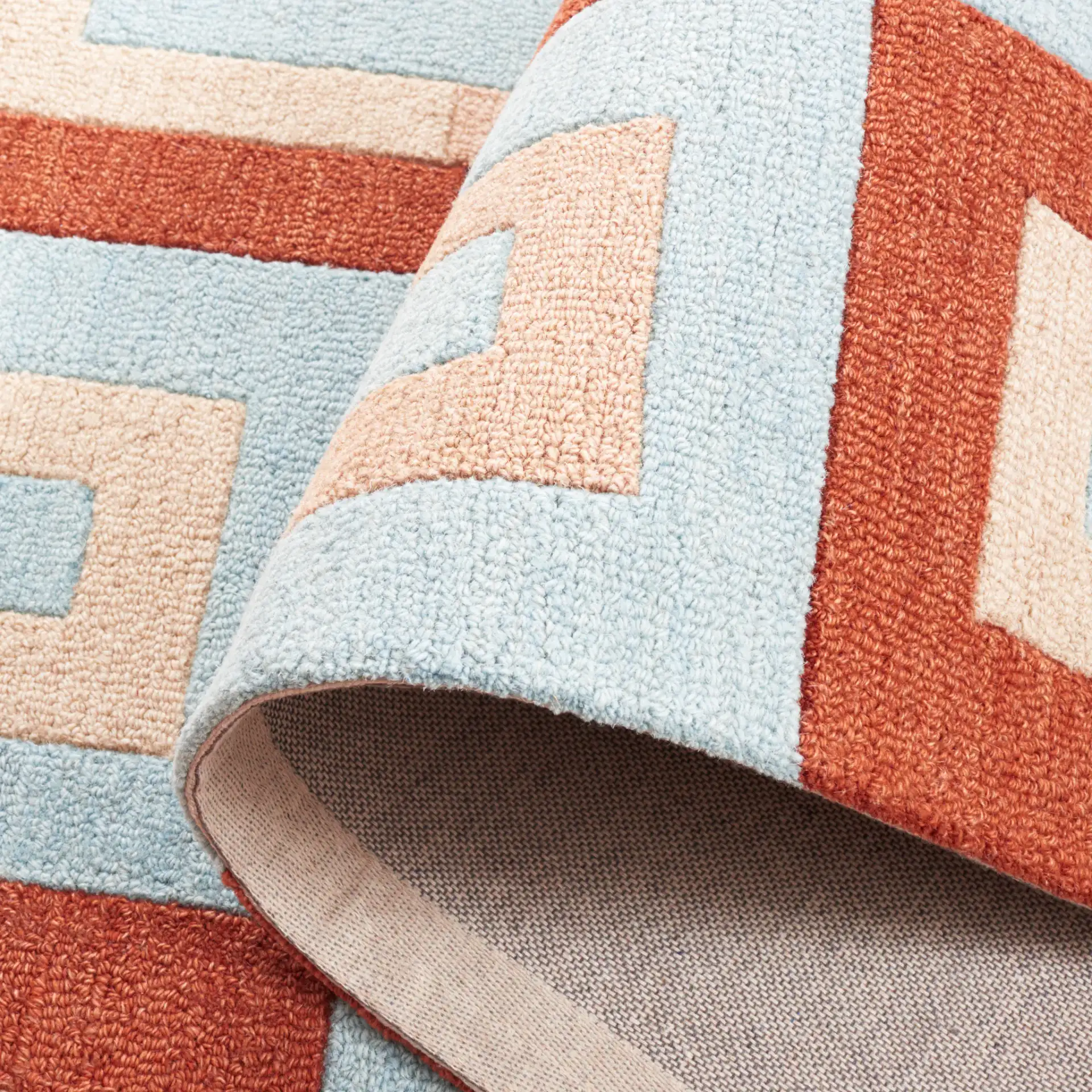Genre Interlocking Rectangles Hand-Tufted Wool Rug in Light Blue / Rust in a styled room