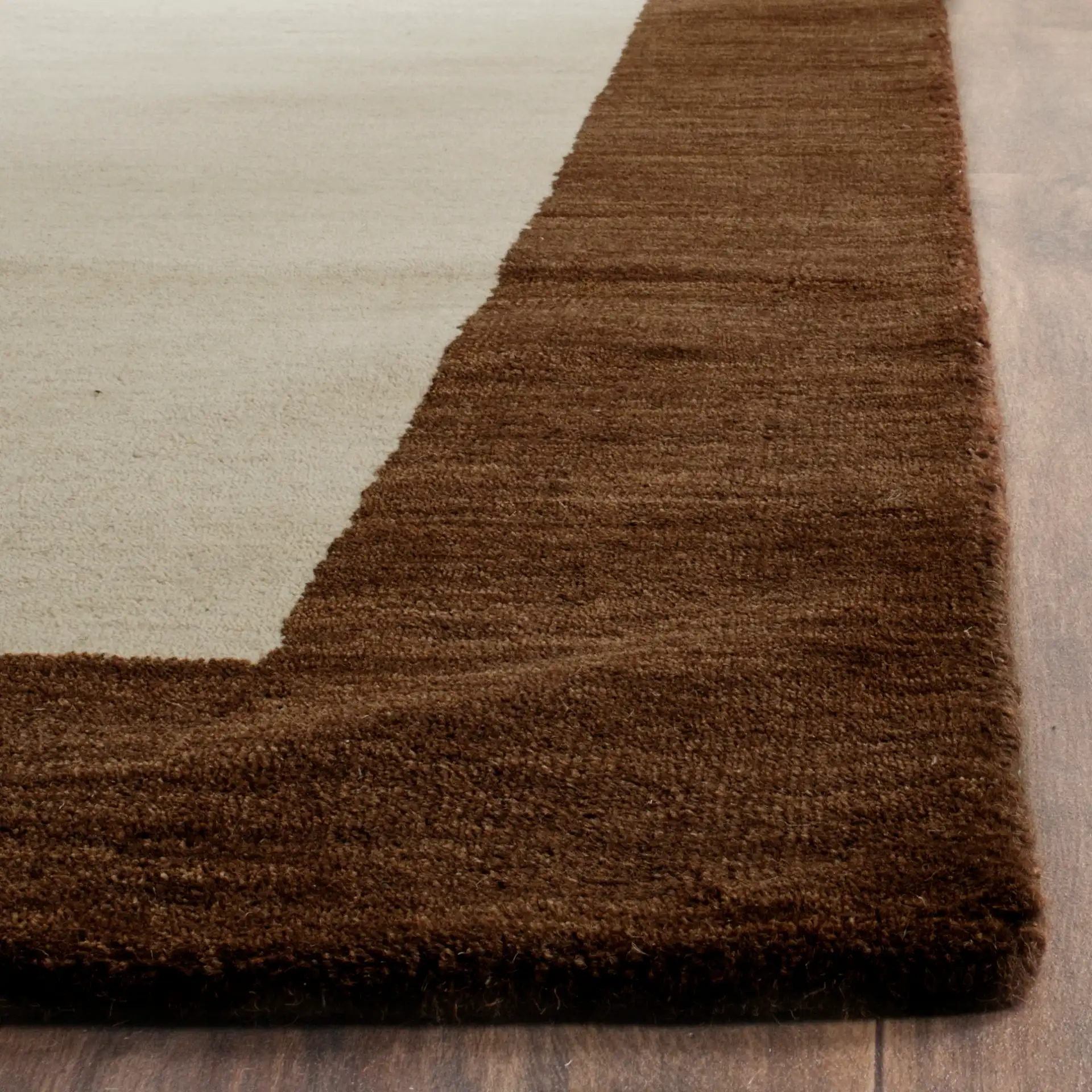 Himalaya Solid Bordered Hand-Loomed Wool Rug in Beige / Dark Brown in a styled room