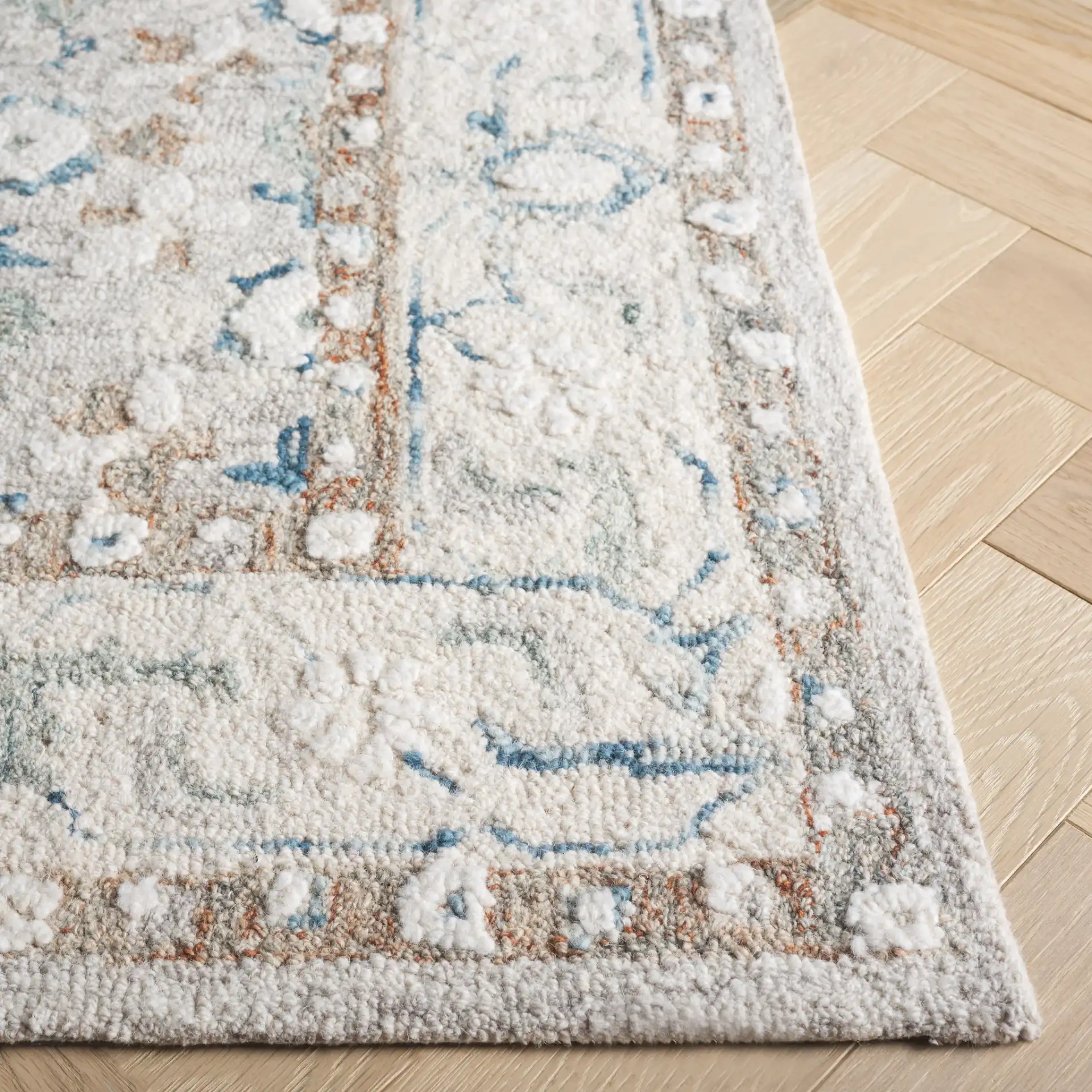 Metro Rosette Bordered Hand-Tufted Wool Rug in Ivory / Blue in a styled room