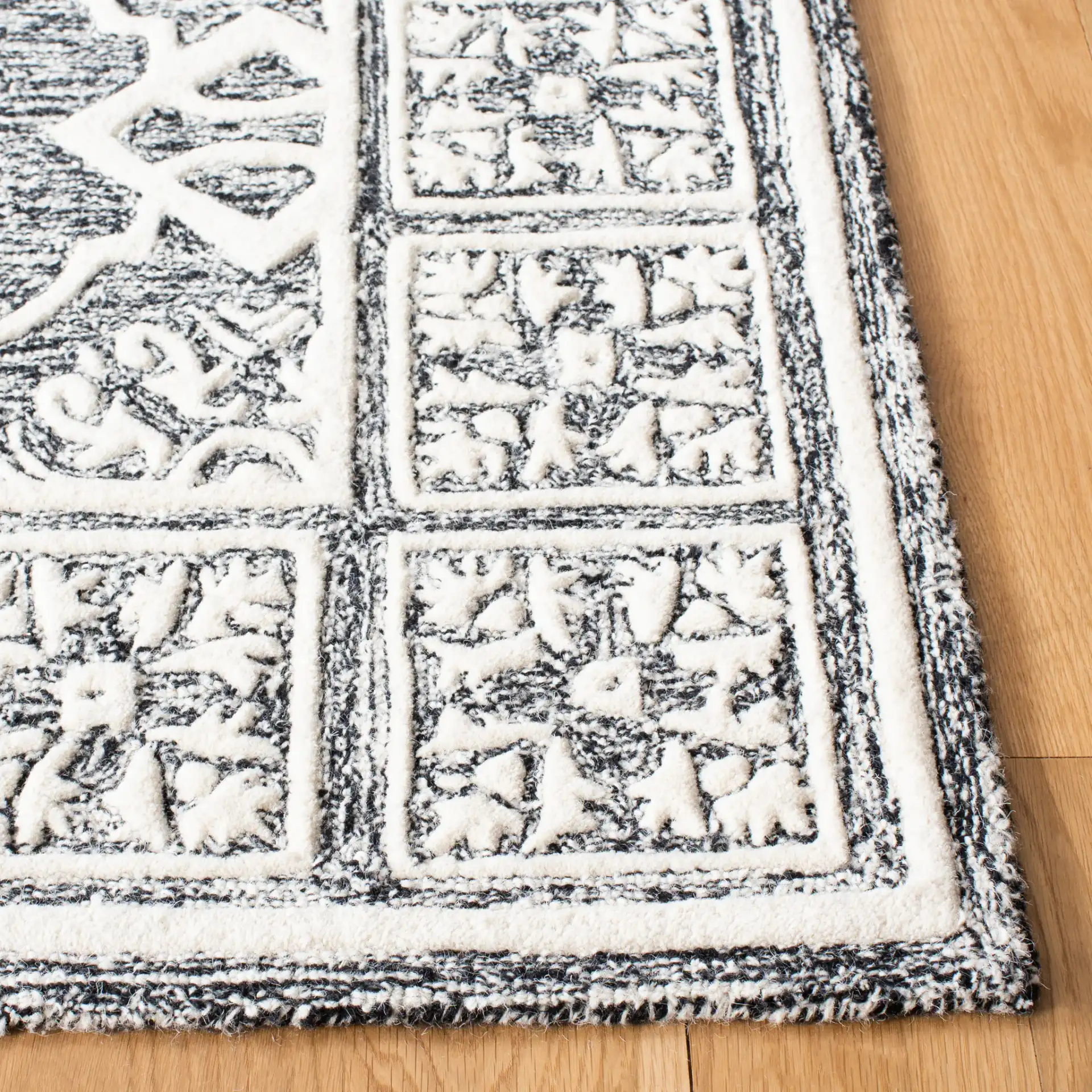Metro Tile Bordered Hand-Tufted Wool Rug in Black / Ivory in a styled room