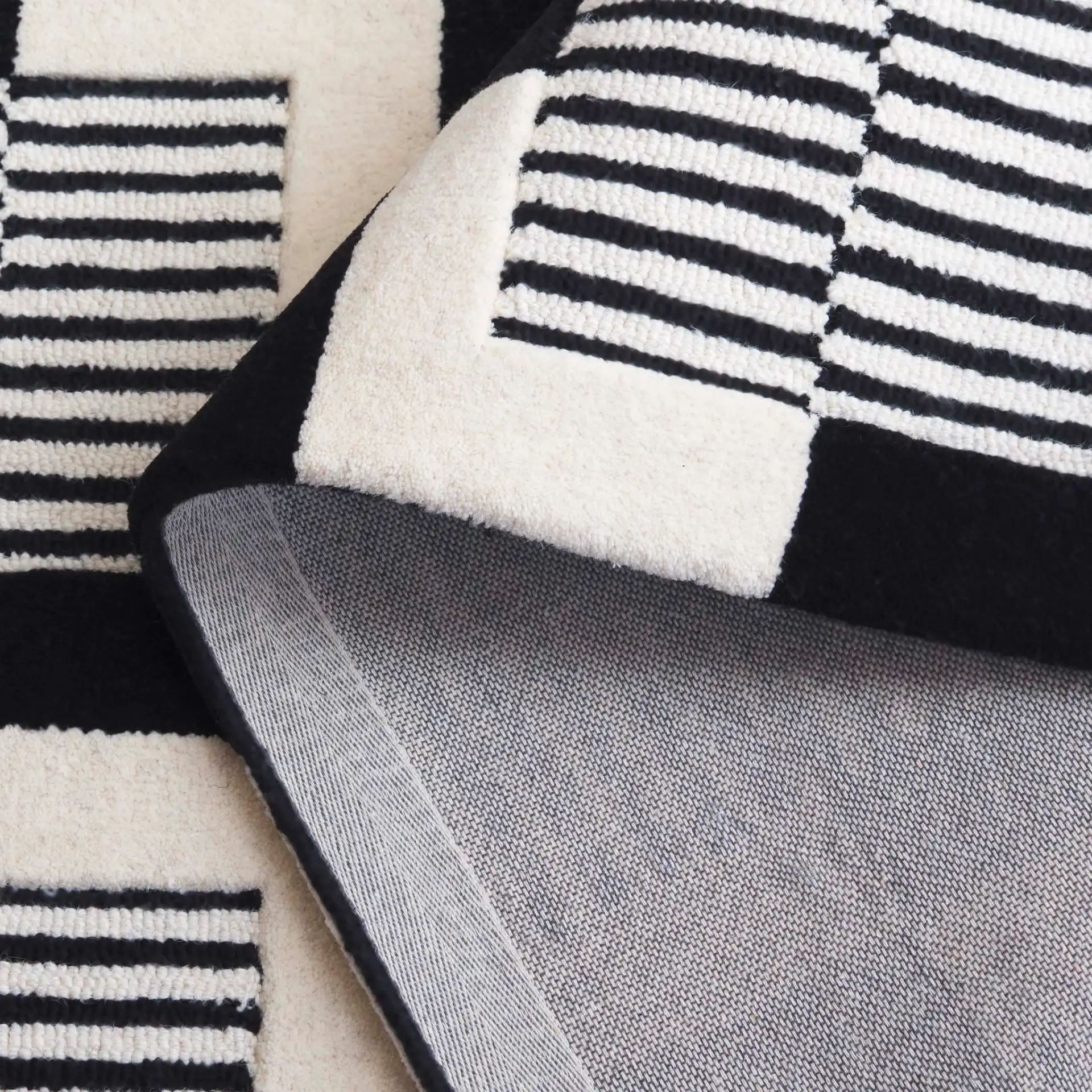 Metro Striped Checkerboard Hand-Tufted Wool Rug in Black / Ivory in a styled room