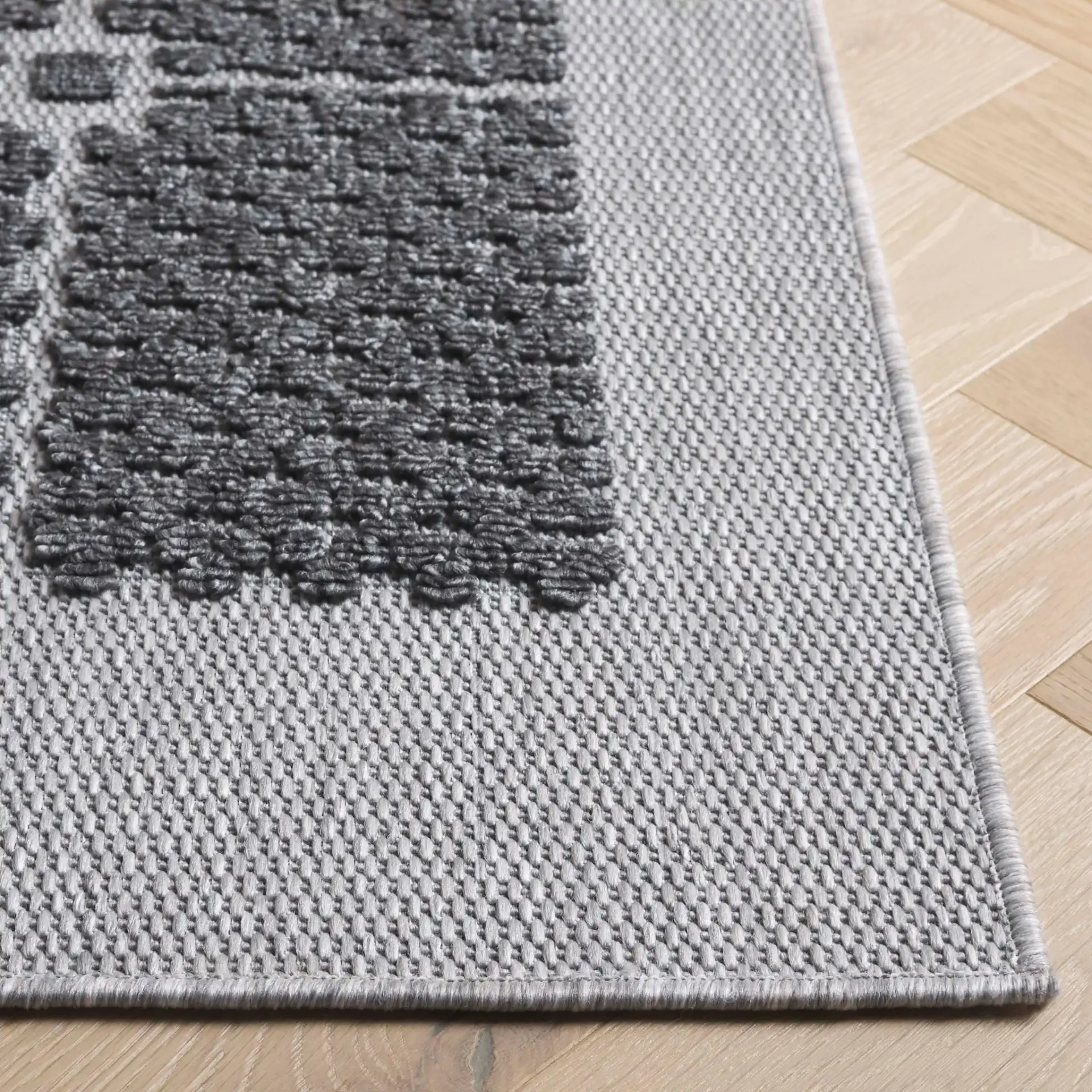 Milos Grid Border Outdoor Rug in Charcoal in a styled room