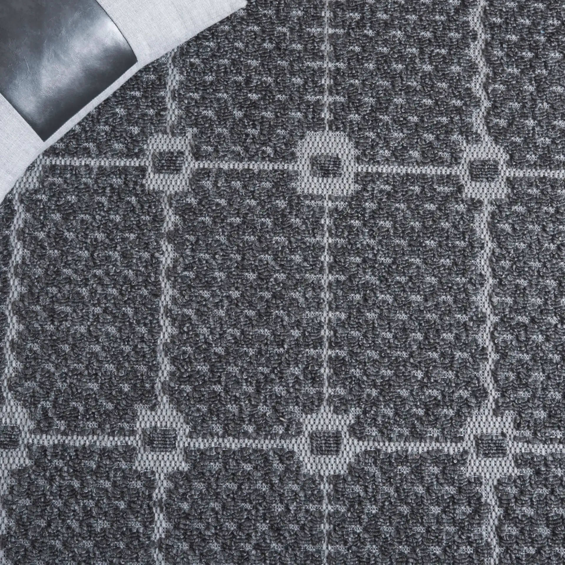 Milos Grid Border Outdoor Rug in Charcoal in a styled room