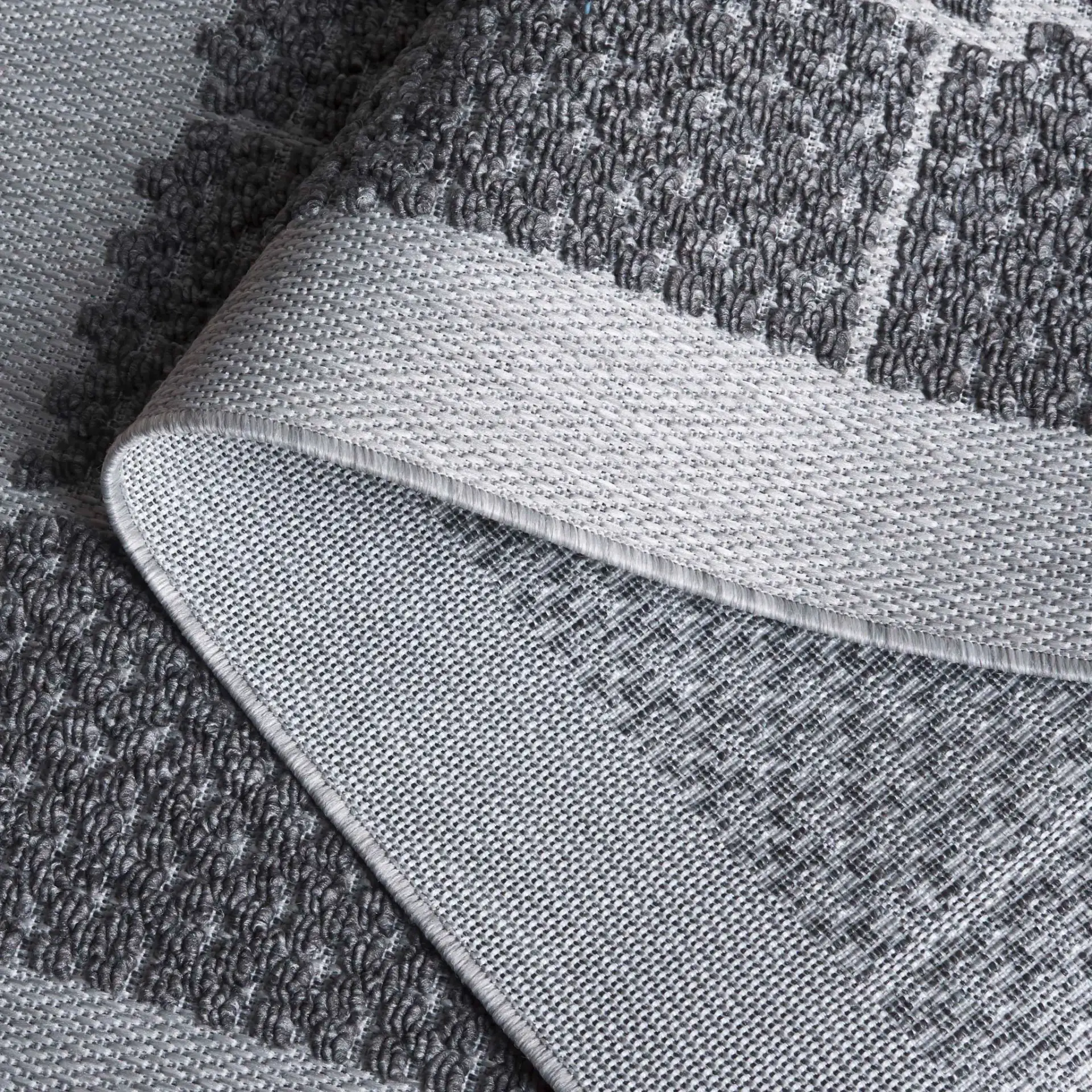 Milos Grid Border Outdoor Rug in Charcoal in a styled room