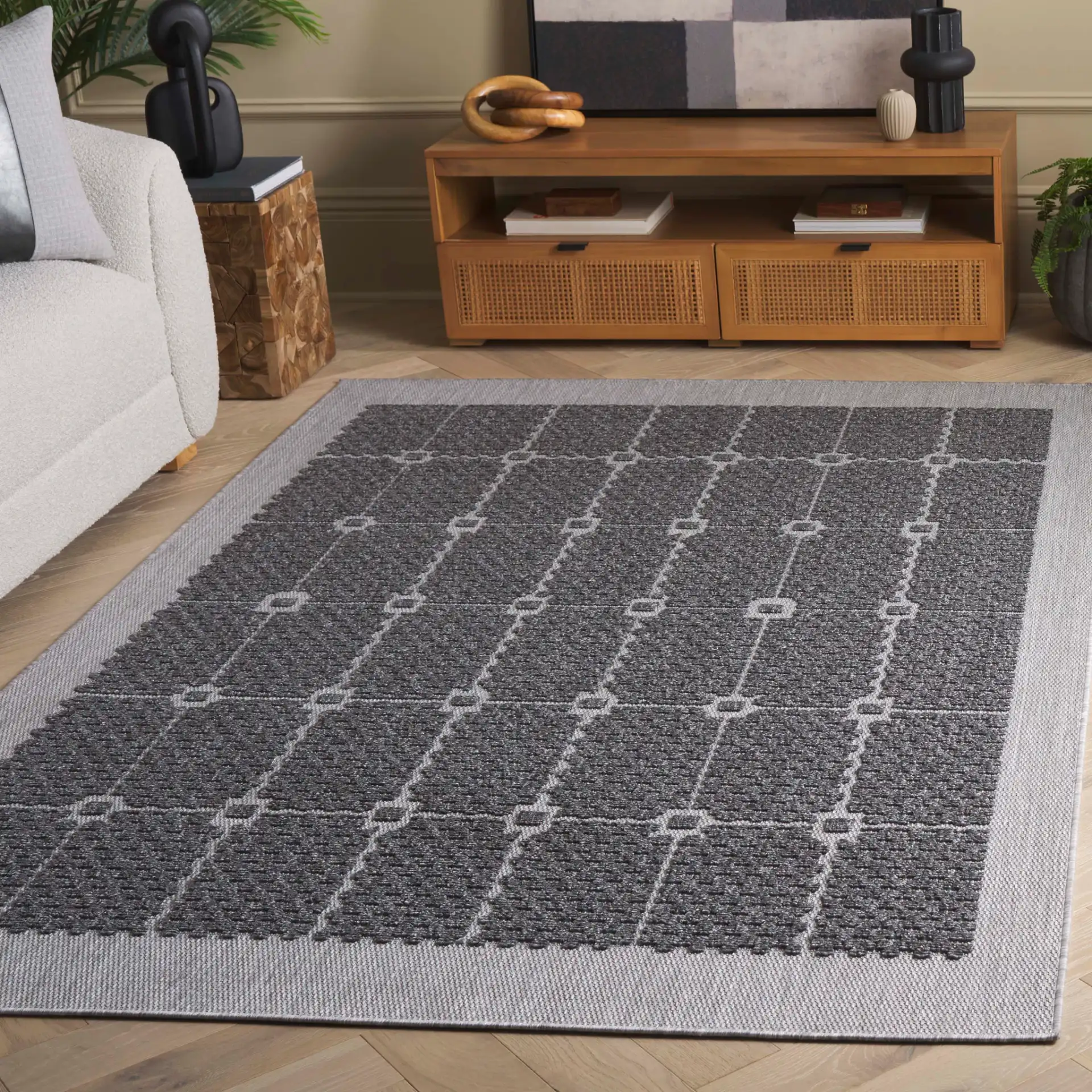 Milos Grid Border Outdoor Rug in Charcoal in a styled room