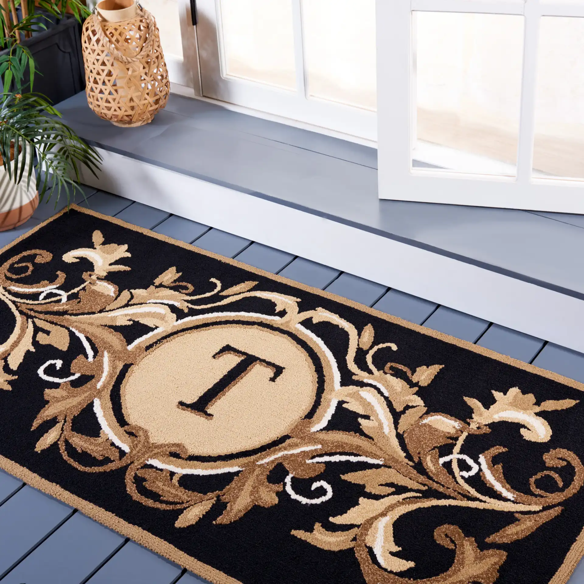 Monogram Leafy Initial Hand-Hooked Outdoor Rug in Black / Brown in a styled room