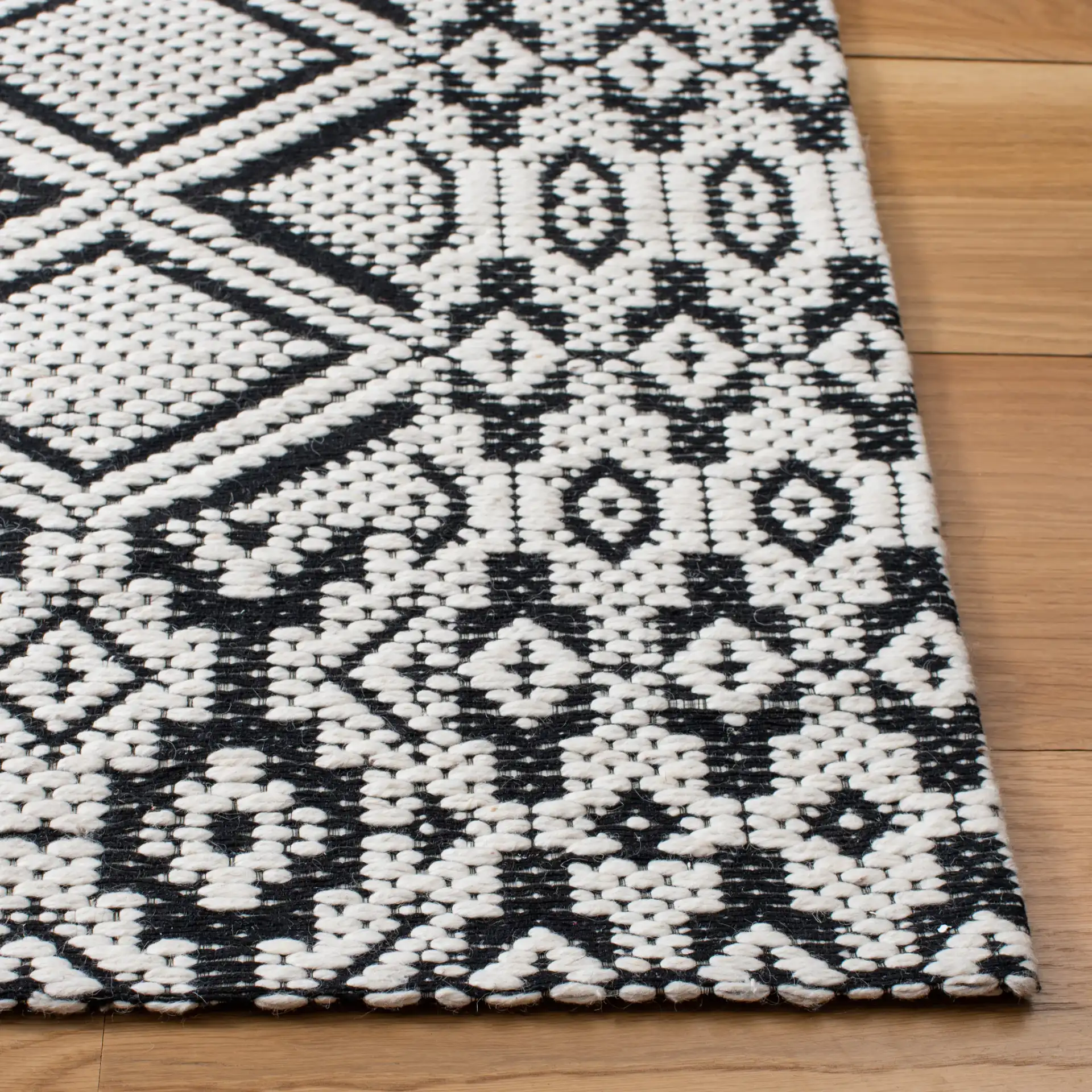 Marbella Diamond Border Hand-Woven Wool Rug in Ivory / Black in a styled room