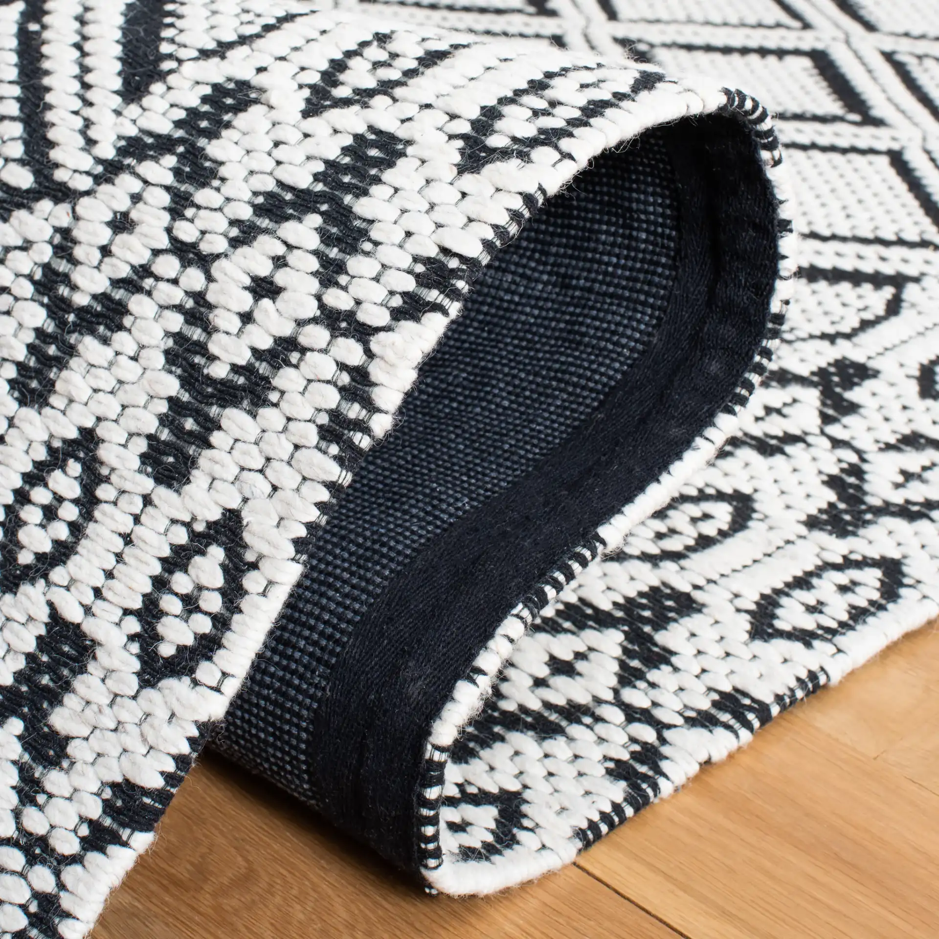 Marbella Diamond Border Hand-Woven Wool Rug in Ivory / Black in a styled room