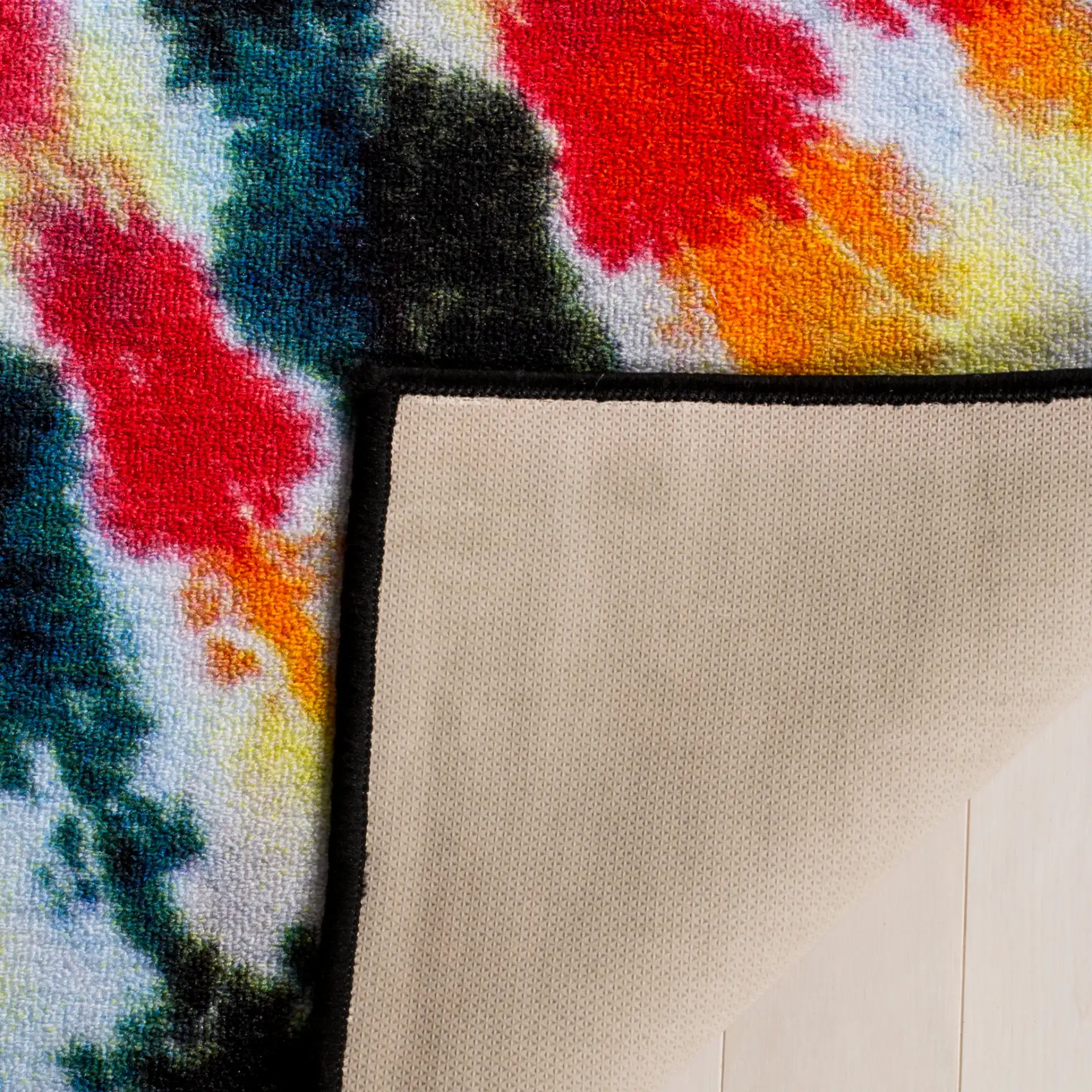 Paint Brush Tie-Dye Spiral Washable Rug in Black / Coral in a styled room